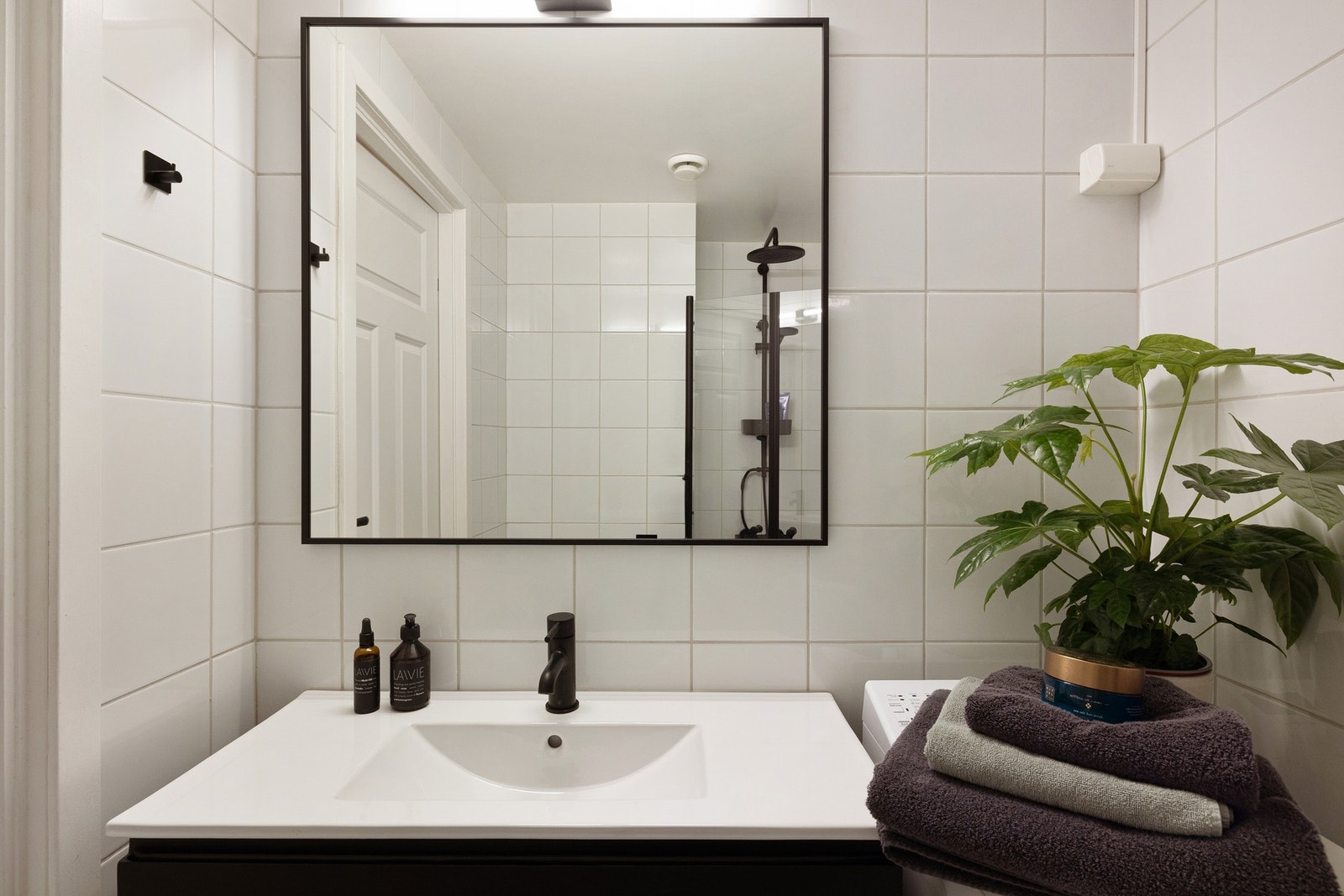 Moderne baderomsinnredning med skuffer og heldekkende sevant, stor speil med belysning over. Galleribilde