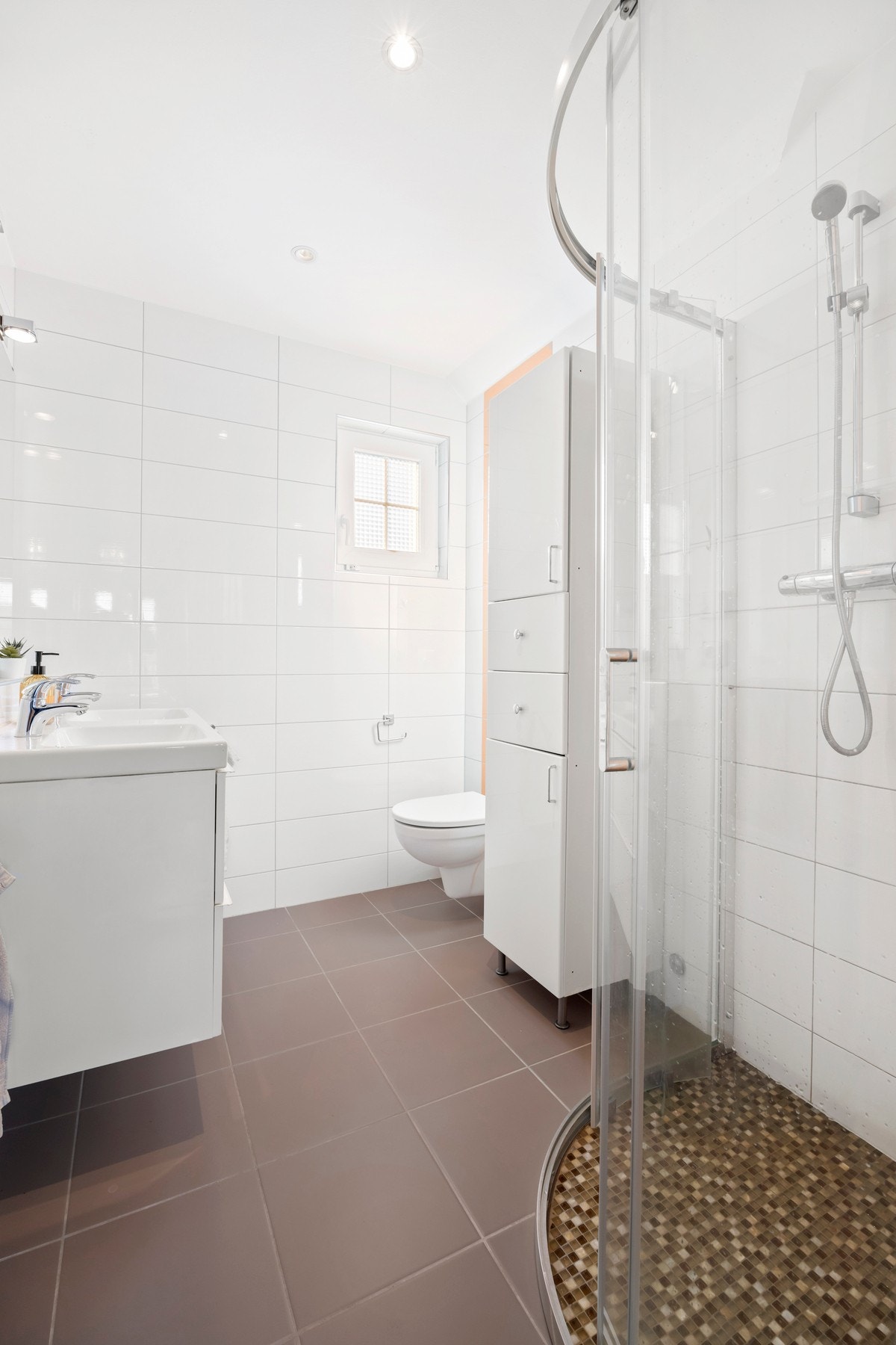 Lyst bad med vegghengt toalett, dusjhjørne og dobbelt servant Galleribilde