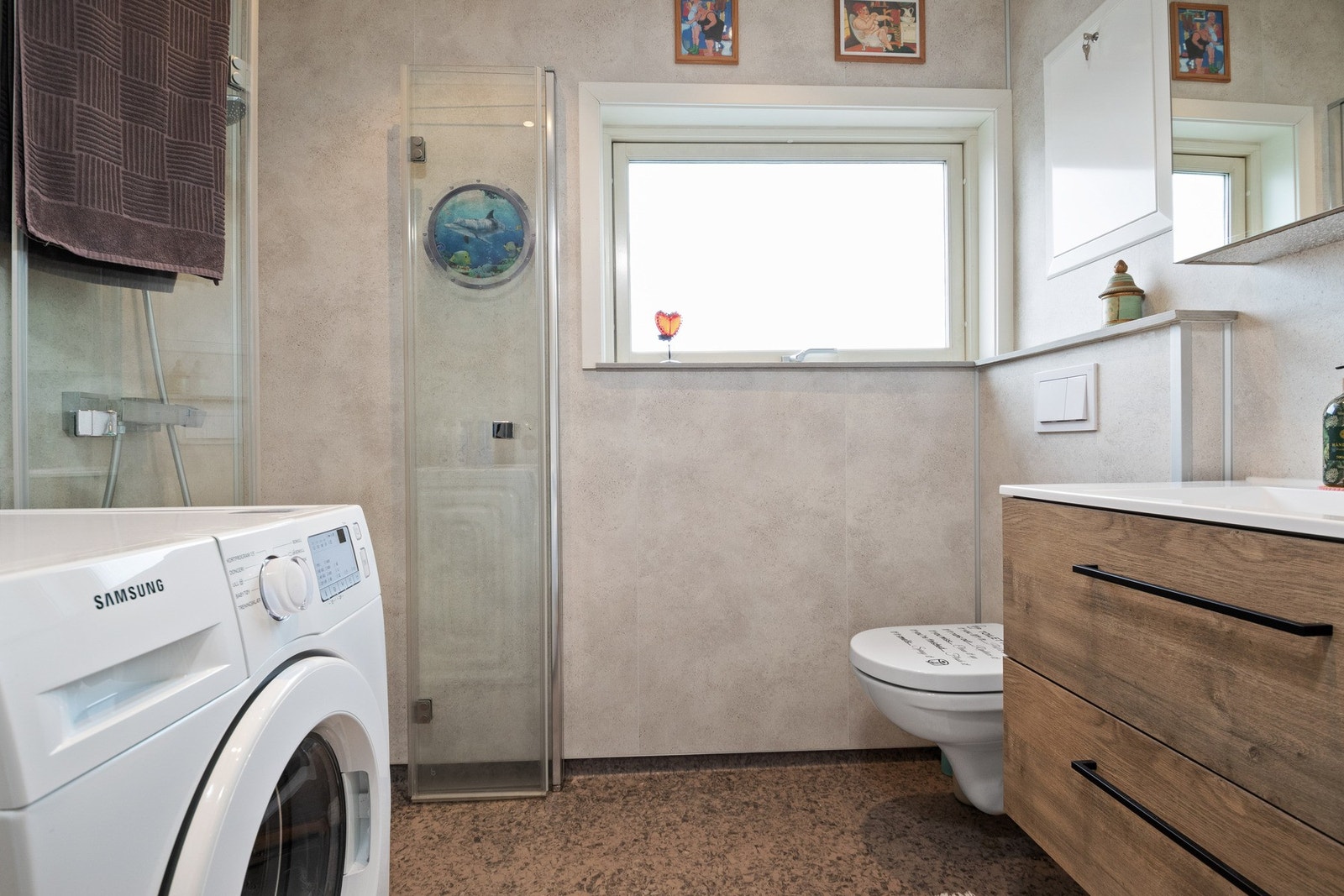 Badet er fra 2022 og fremstår som pent utført med mørk gulvbelegg, lyse baderomsplater på veggene Galleribilde