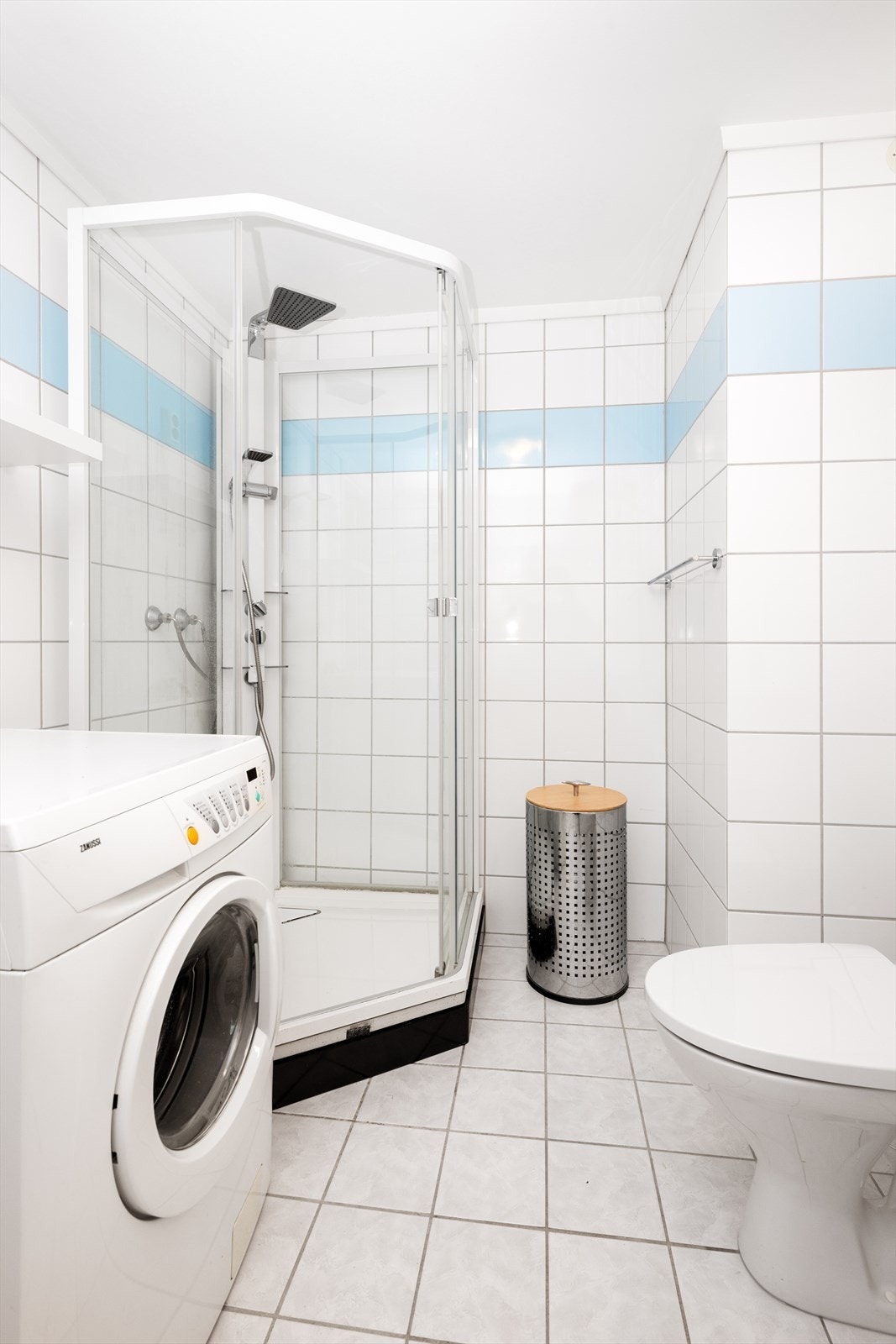 Badet er innredet med toalett, dusjkabinett og servantinnredning med underskap, overskap og speil med overlys og el-stikk. Det er mekanisk avtrekk. Galleribilde