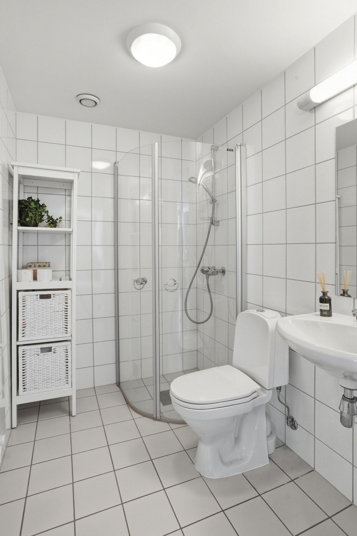 Gjestebad med gulvstående toalett, servantinnredning og dusjhjørne med innfellbare vegger Galleribilde