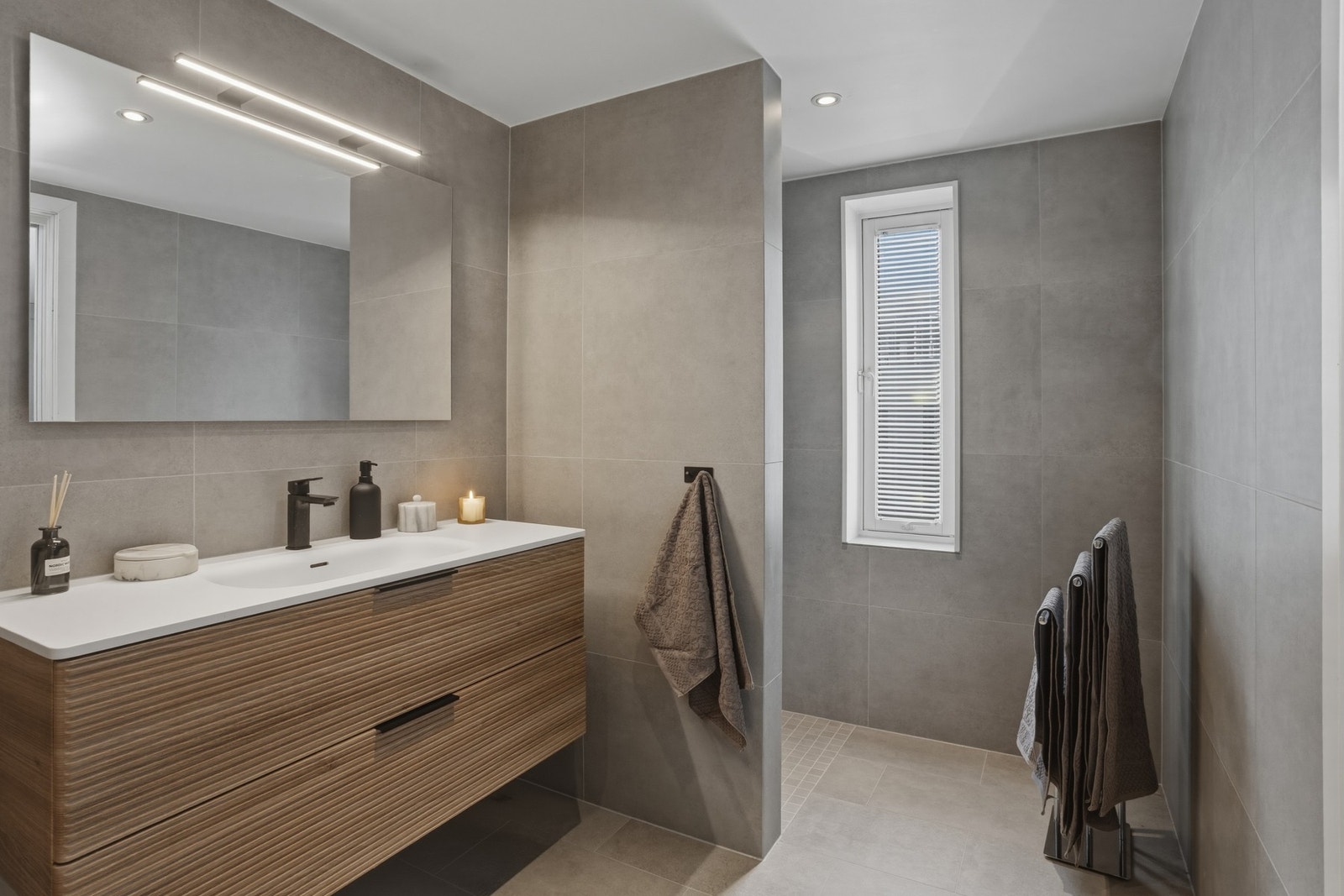 Badet er innredet med servantinnredning, speil og dusjnisje Galleribilde