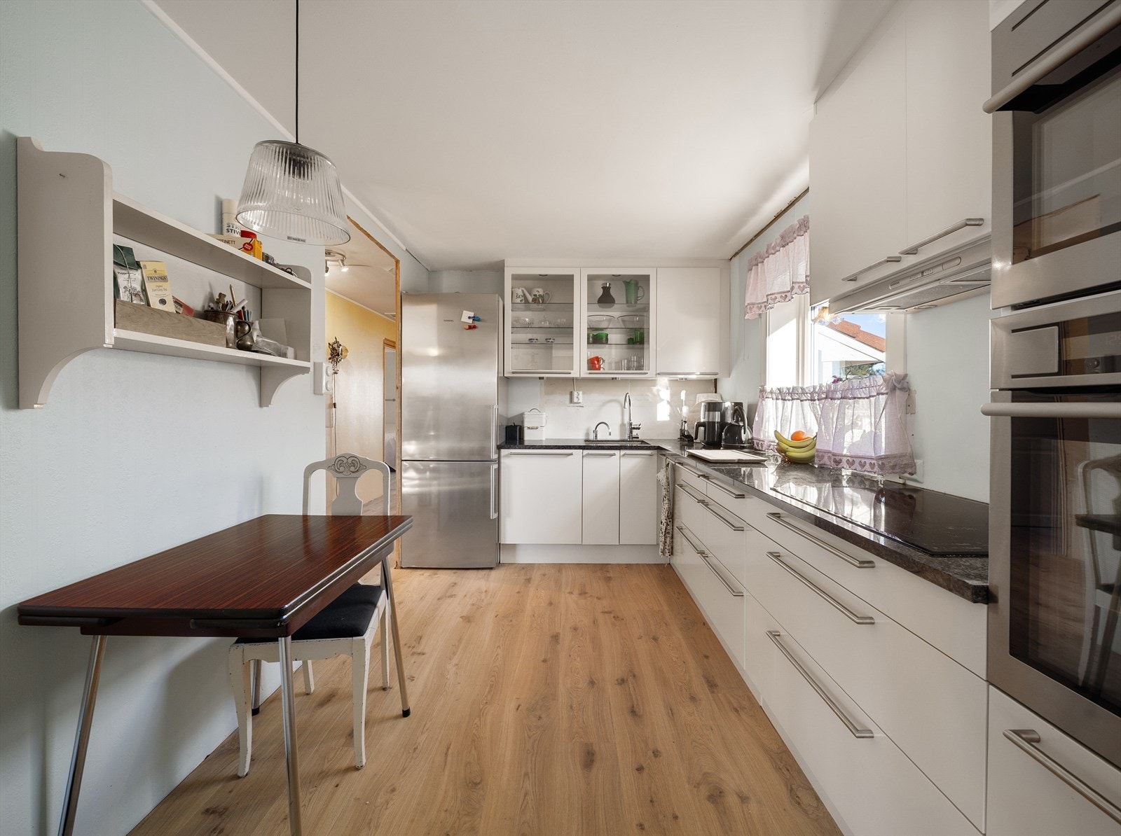 Pent kjøkken med innredning fra HTH med slette fronter, benkeplate av kompositt/stein, oppvaskmaskin, mikro, steikeovn og platetopp. Galleribilde