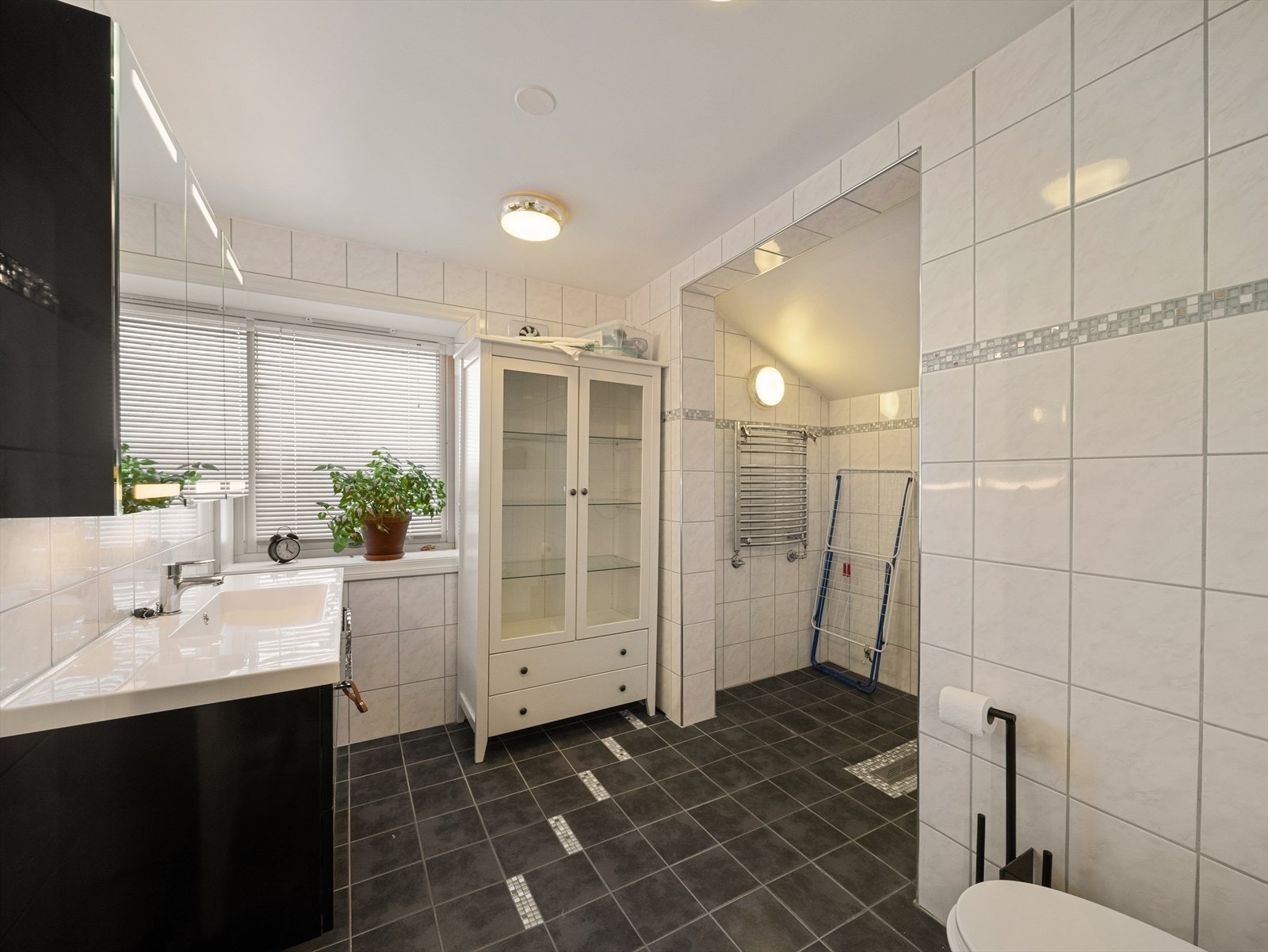 Helfliset bad innredet med baderomsinnredning med servant, vegghengt toalett og stor dusjnisje. Galleribilde