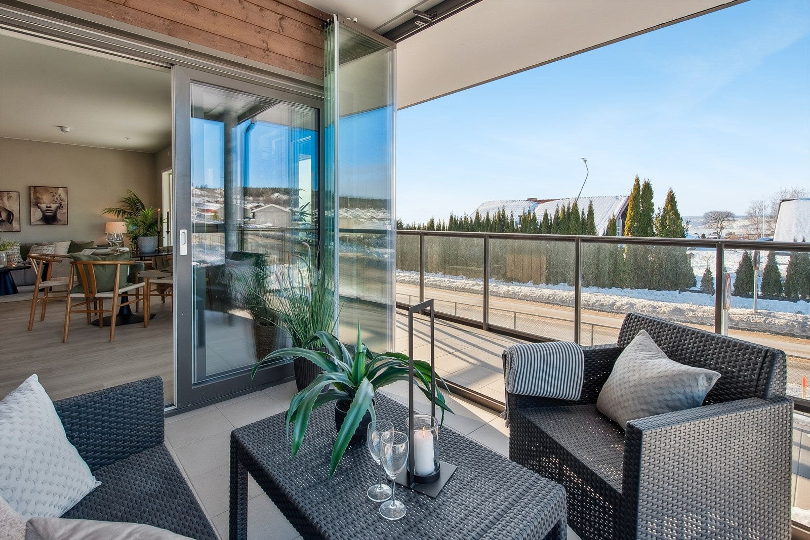 Stor flislagt balkong som er delvis innglasset, strekker seg rundt hjørnet på bygget slik at man følger sola fra formiddag til sene kveldstimer. Galleribilde