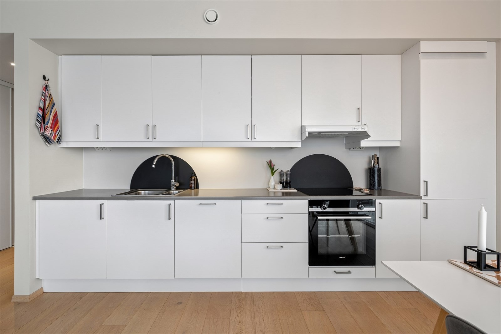 Kjøkkeninnredningen har glatte fronter og laminat benkeplate med nedfelt kum i rustfritt stål. Galleribilde