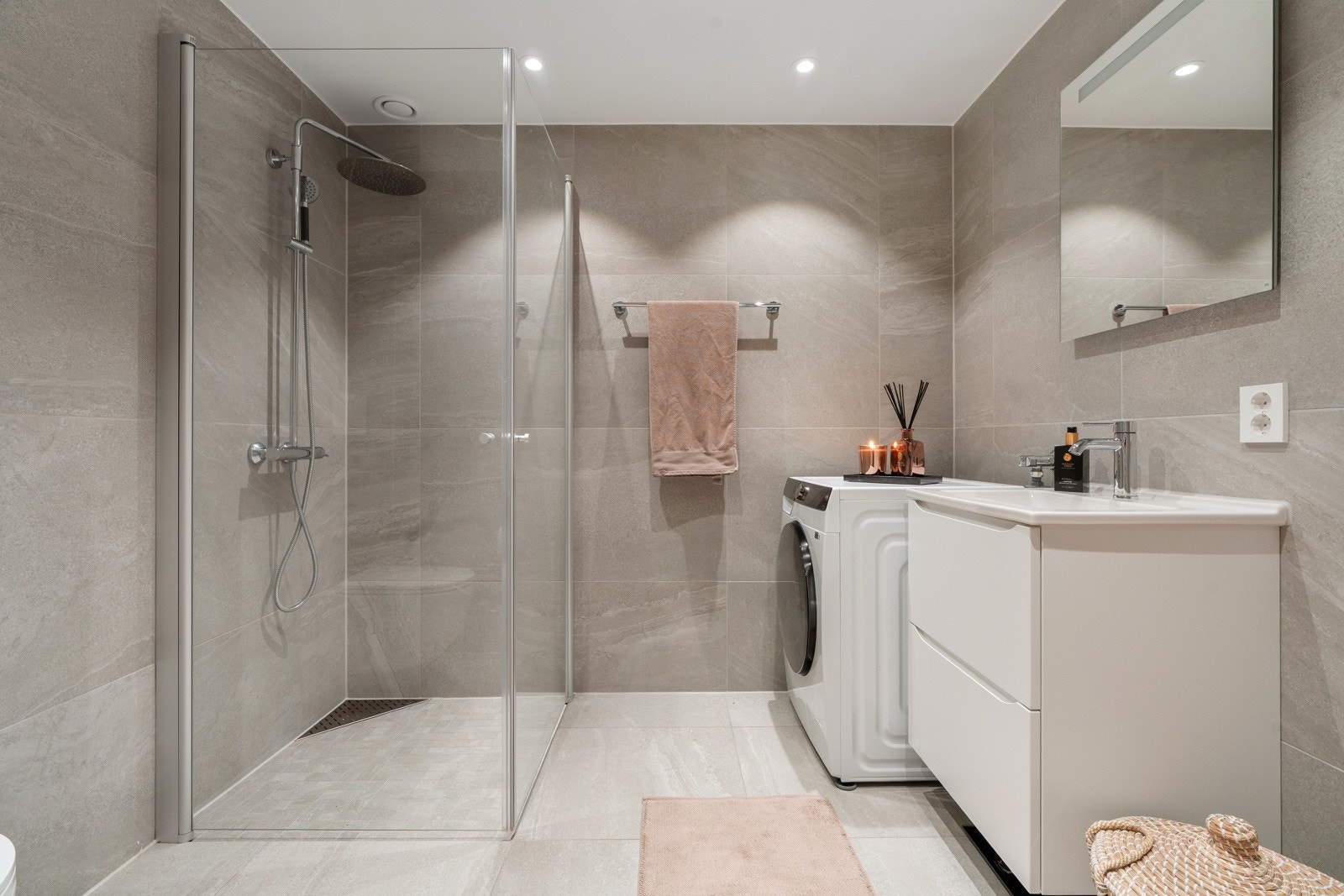 Nydelig flislagt bad - utstyrt med stort dusjhjørne, opplegg for vaskemaskin, praktisk vegghengt toalett, samt innredning med god oppbevaringsplass.