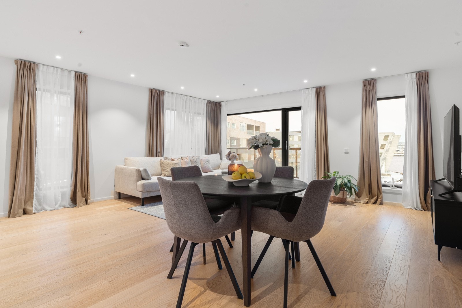 Stuen framstår åpen, lys og luftig, med store vindusflater og generøs takhøyde.