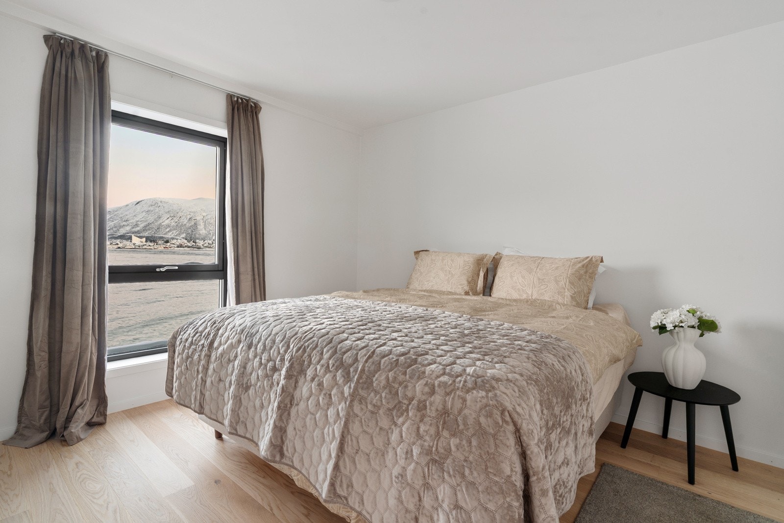 Leilighetens første soverom framstår romslig, med god plass for stor seng og tilhørende nattbord.