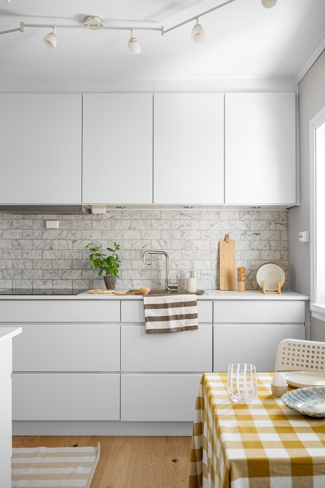 Veggen mellom benkeplaten og overskapene er belagt med elegante fliser i Carrara-marmor. Galleribilde