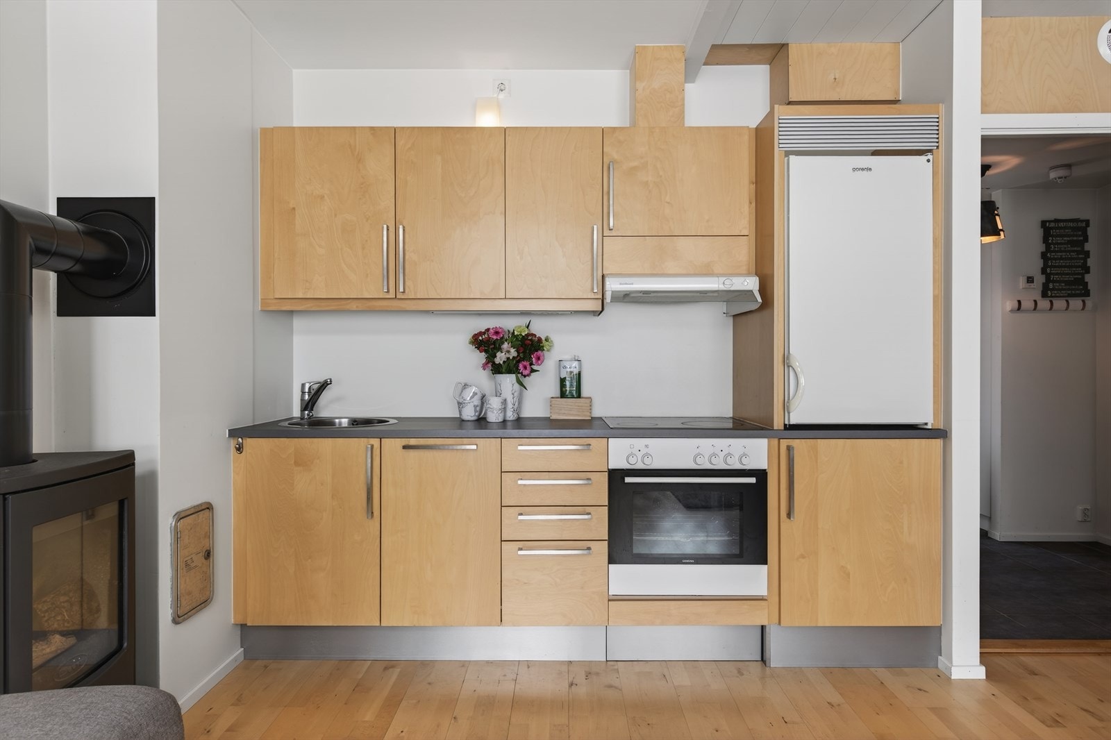 Pent kjøkken med integrerte hvitevarer som stekeovn, platetopp og oppvaskmaskin. Frittstående kjøleskap Galleribilde