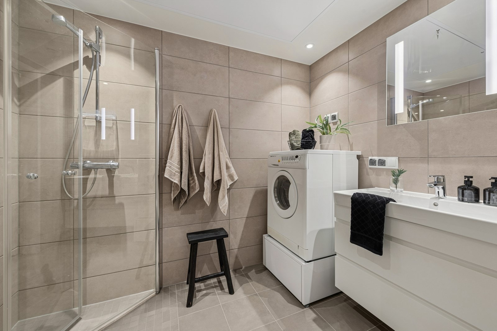 Badet er utstyrt med nedsenket servant med 1-greps blandebatteri, speil med lys, vegghengt toalett, opplegg for vaskemaskin og innfellbare dusjvegger. Galleribilde