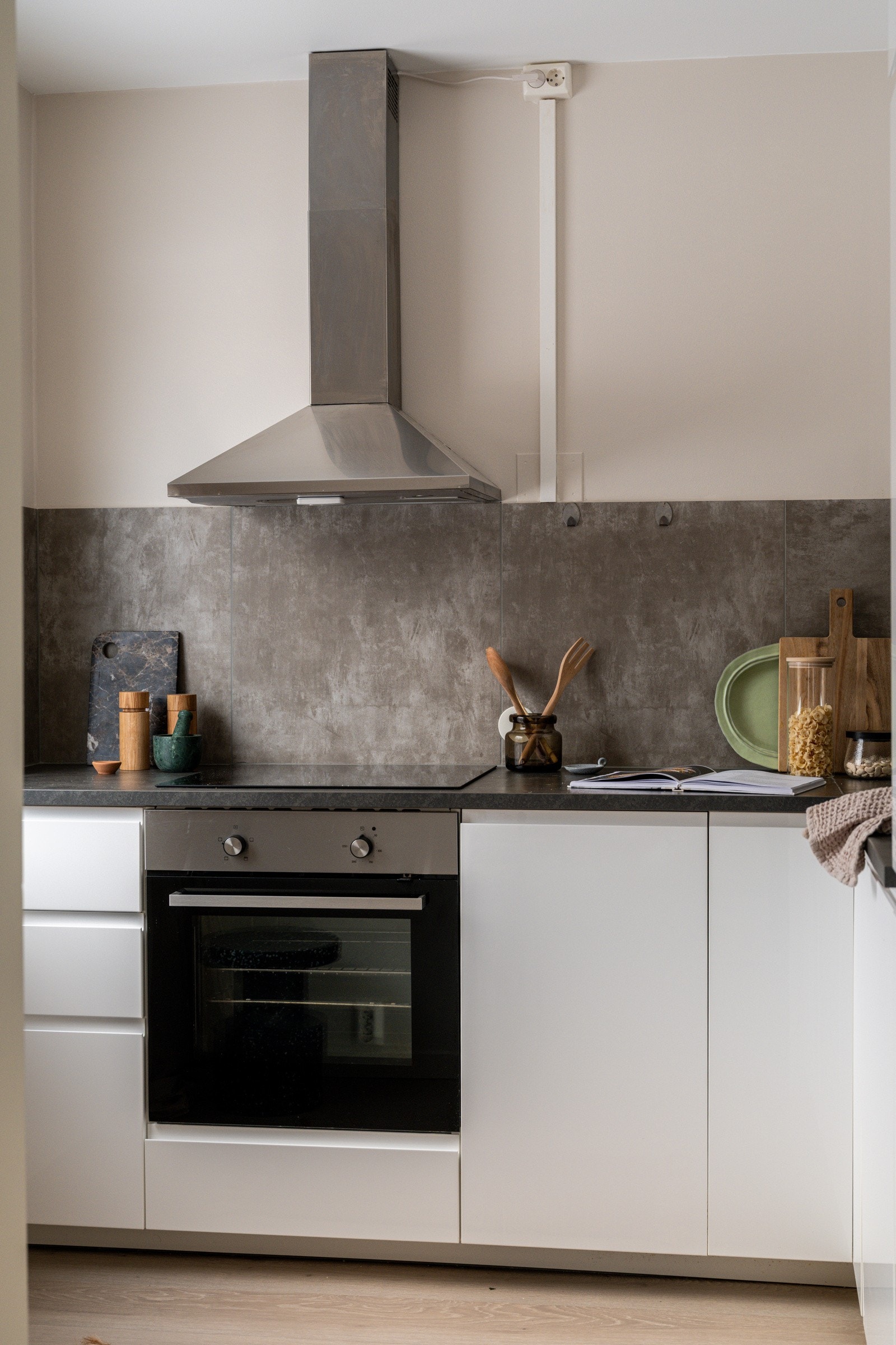 Lyst og moderne Ikea-kjøkken fra 2019 med god skap- og benkeplass. Innredningen har hvite glatte fronter og laminert benkeplate med nedfelt oppvaskkum. Både fint of praktisk med fliser i benkeryggen og belysning under overskap. Galleribilde