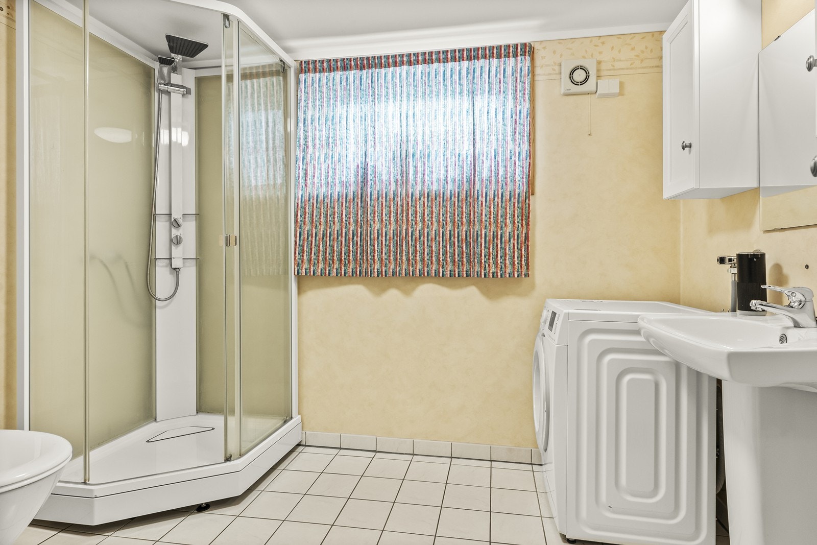 Badet har flislagt gulv med gulvvarme, våtromstapet på veggene og dusjkabinett. Galleribilde