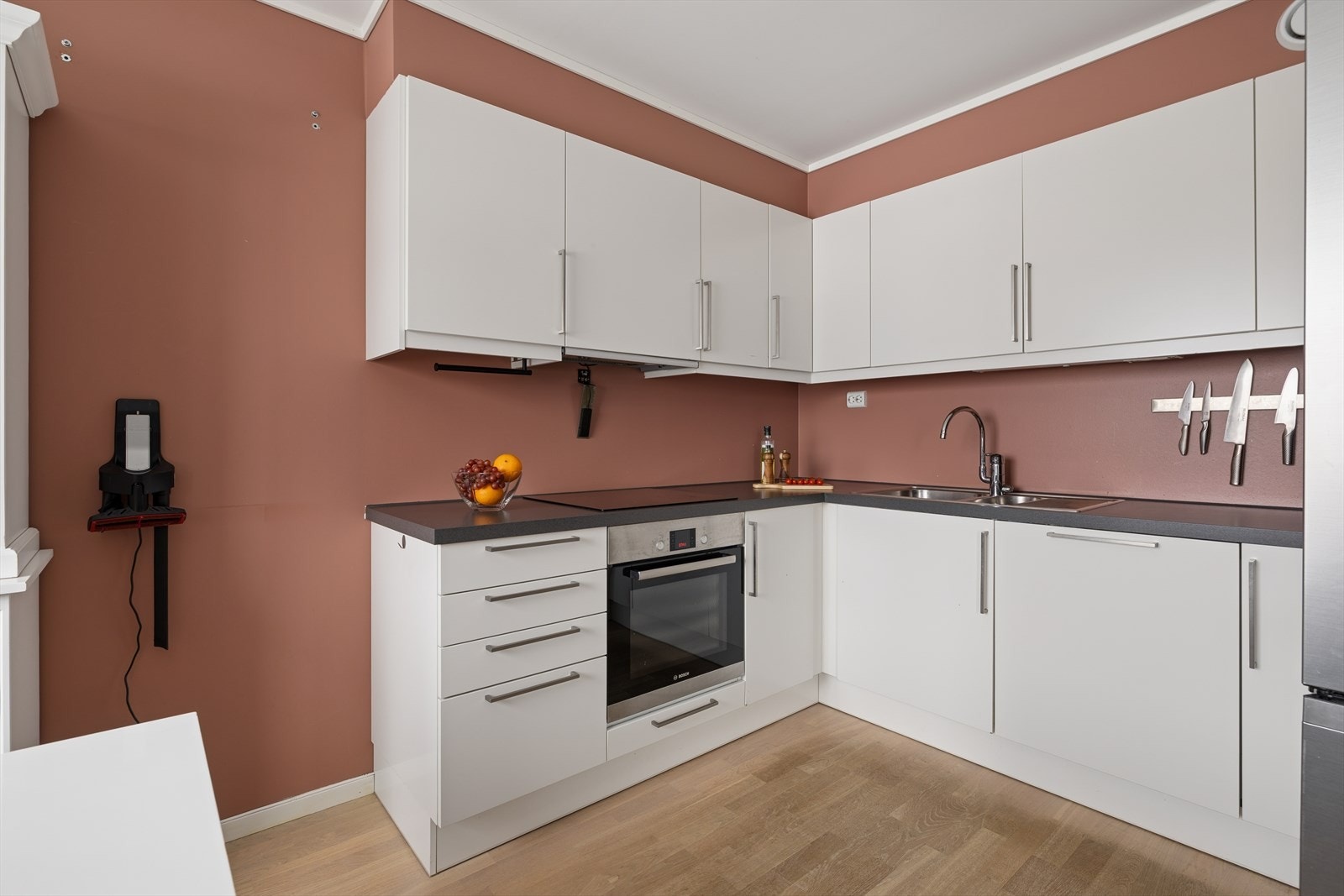 Kjøkkenet har en moderne og stilren utforming, med hvite slette fronter og en mørkere laminat benkeplate som gir et delikat og tidsriktig uttrykk. Galleribilde