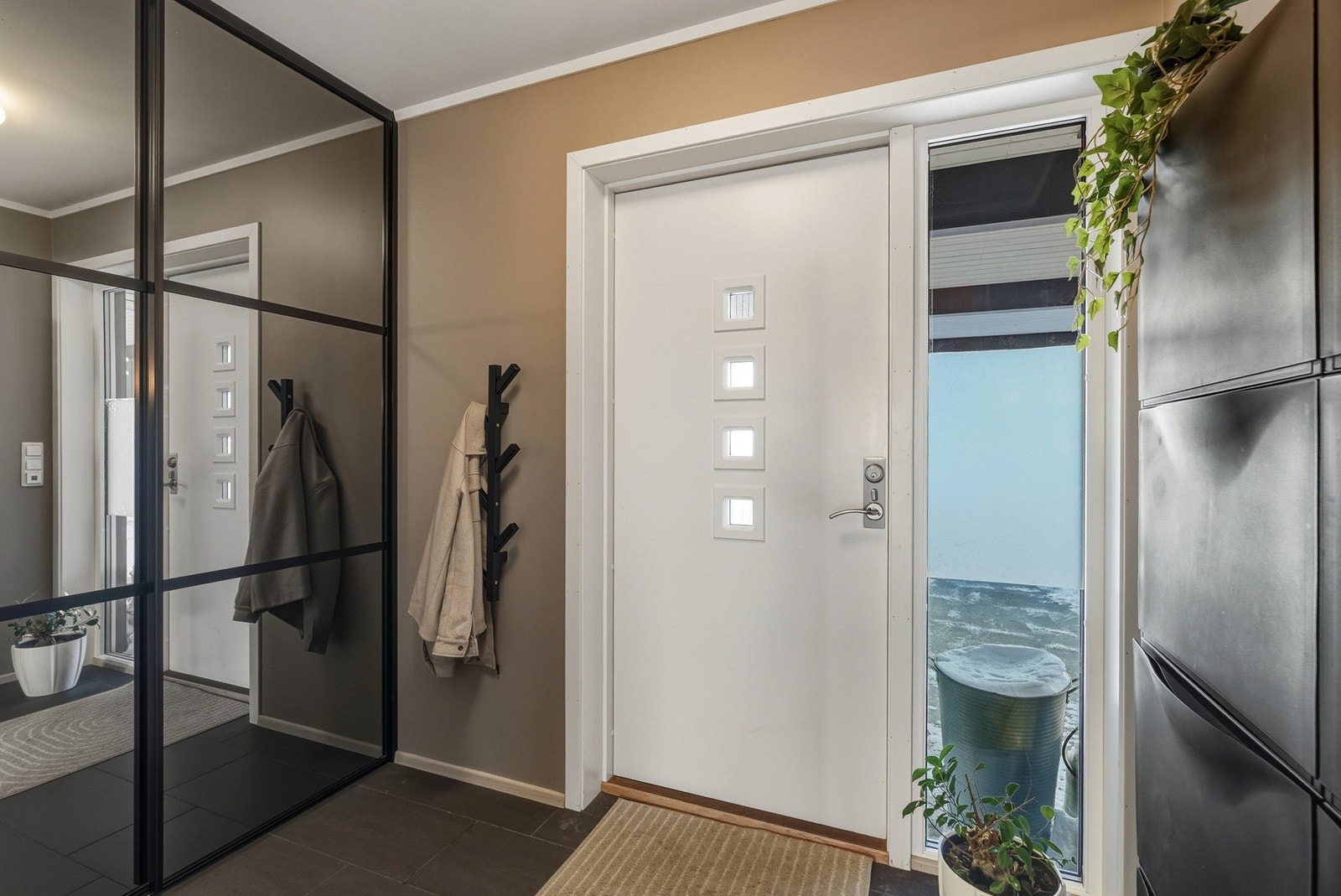 Innbydende entré med flislagt gulv med varmekabler. Skyvedørsgarderobe med speilfronter og skoskap Galleribilde