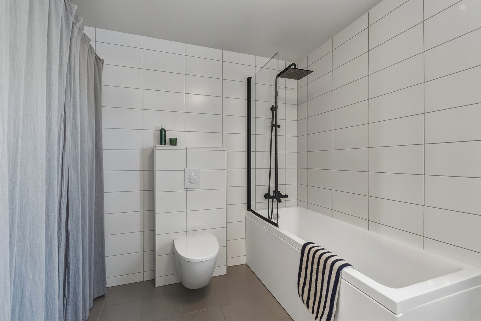 Vegghengt toalett og badekar med skillevegg i glass og både regnfallsdusj/hånddusj. Galleribilde