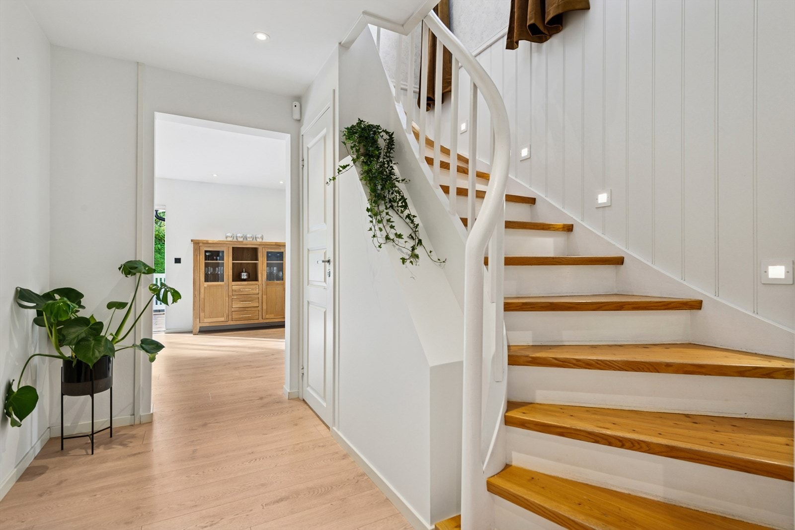 Gang med trapp og lekker belysning som videre leder deg innover i boligens 1. etasje. Galleribilde