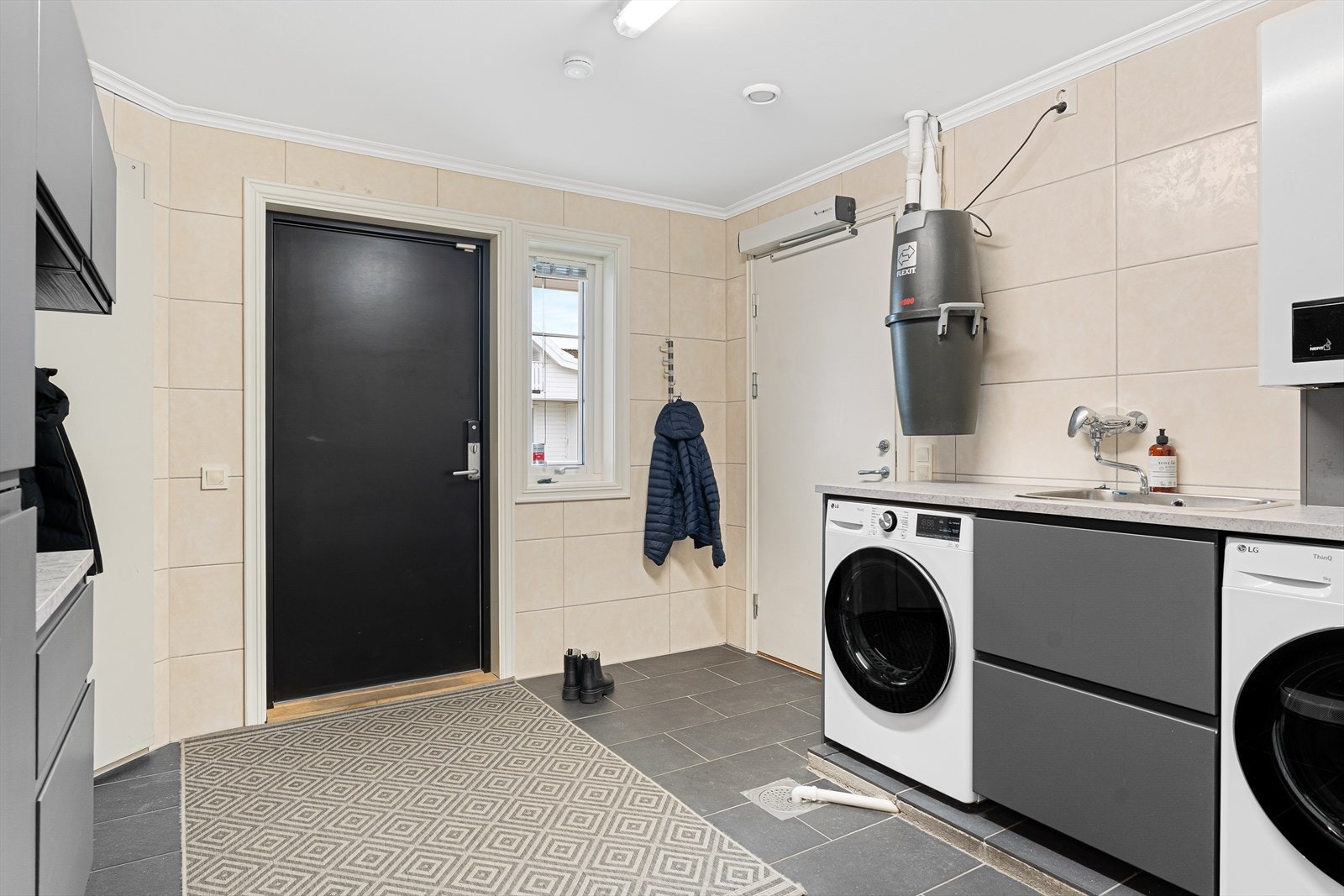 Stort og meget praktisk vaskerom med fliser på vegger og gulv - gulvet har også vannbåren gulvvarme Galleribilde