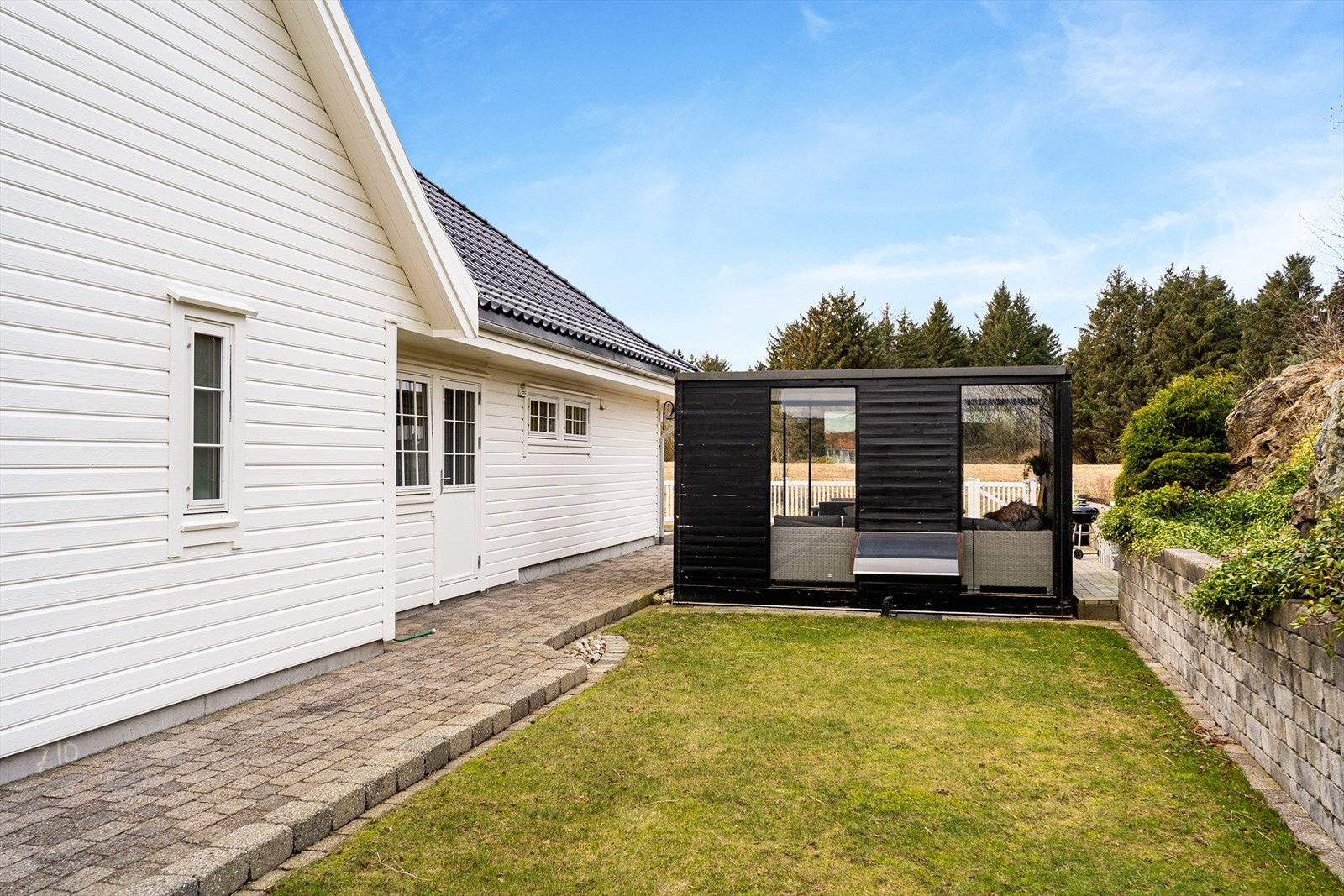 Hagestuen er oppført i trekonstruksjon og kledd med trepanel - det er flat takkonstruksjon samt skyvedør og vinduer med metallprofiler Galleribilde