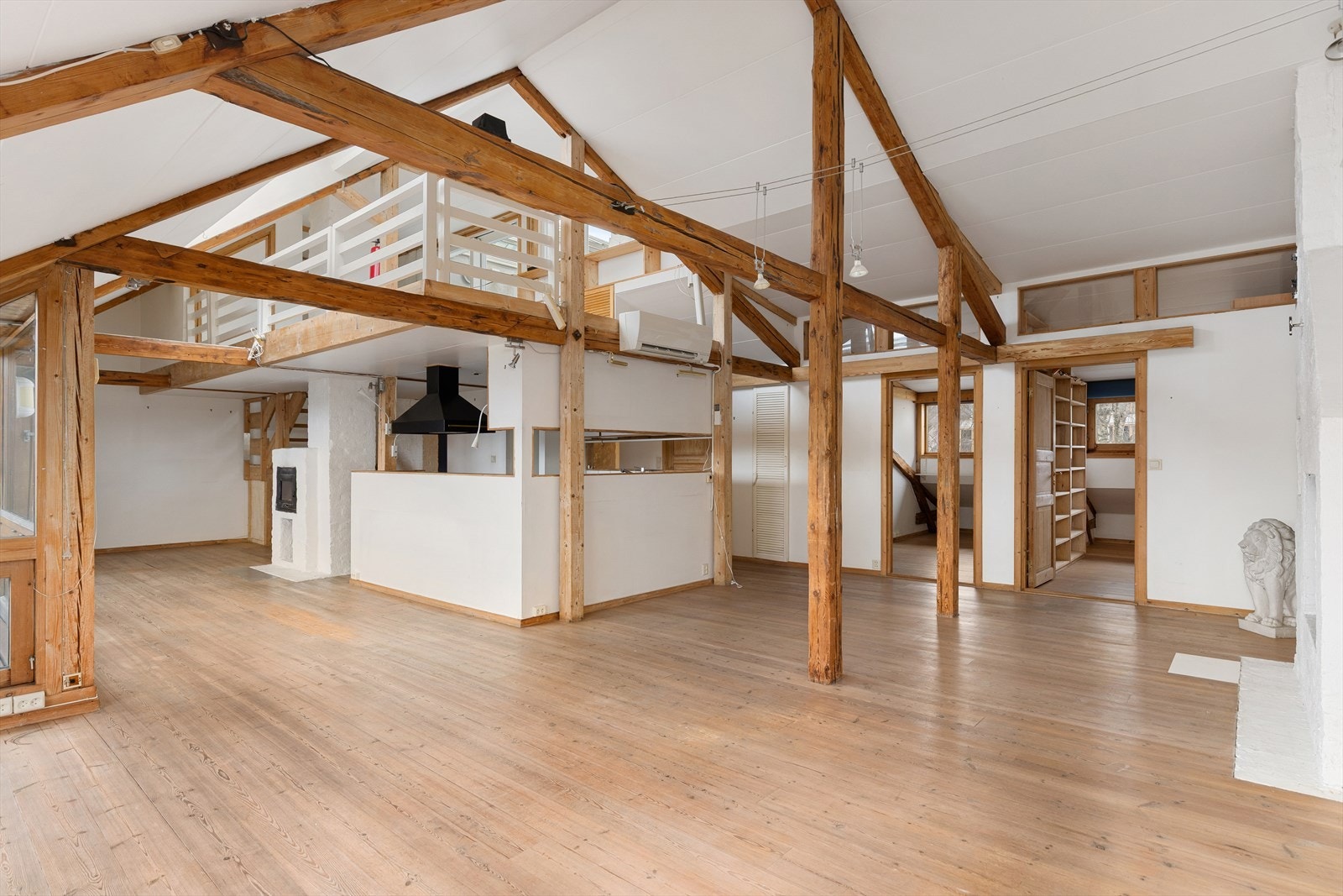 Stor stue med klassiske søyler og bjelker. Kjøkkenet plassert under loftstuen/mezzanin Galleribilde