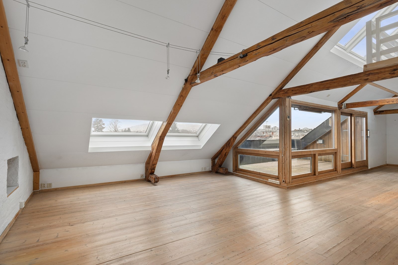 Stor luftig stue med takvinduer i flere plan og godt med lys fra vinduene mot den romslige takterrassen Galleribilde