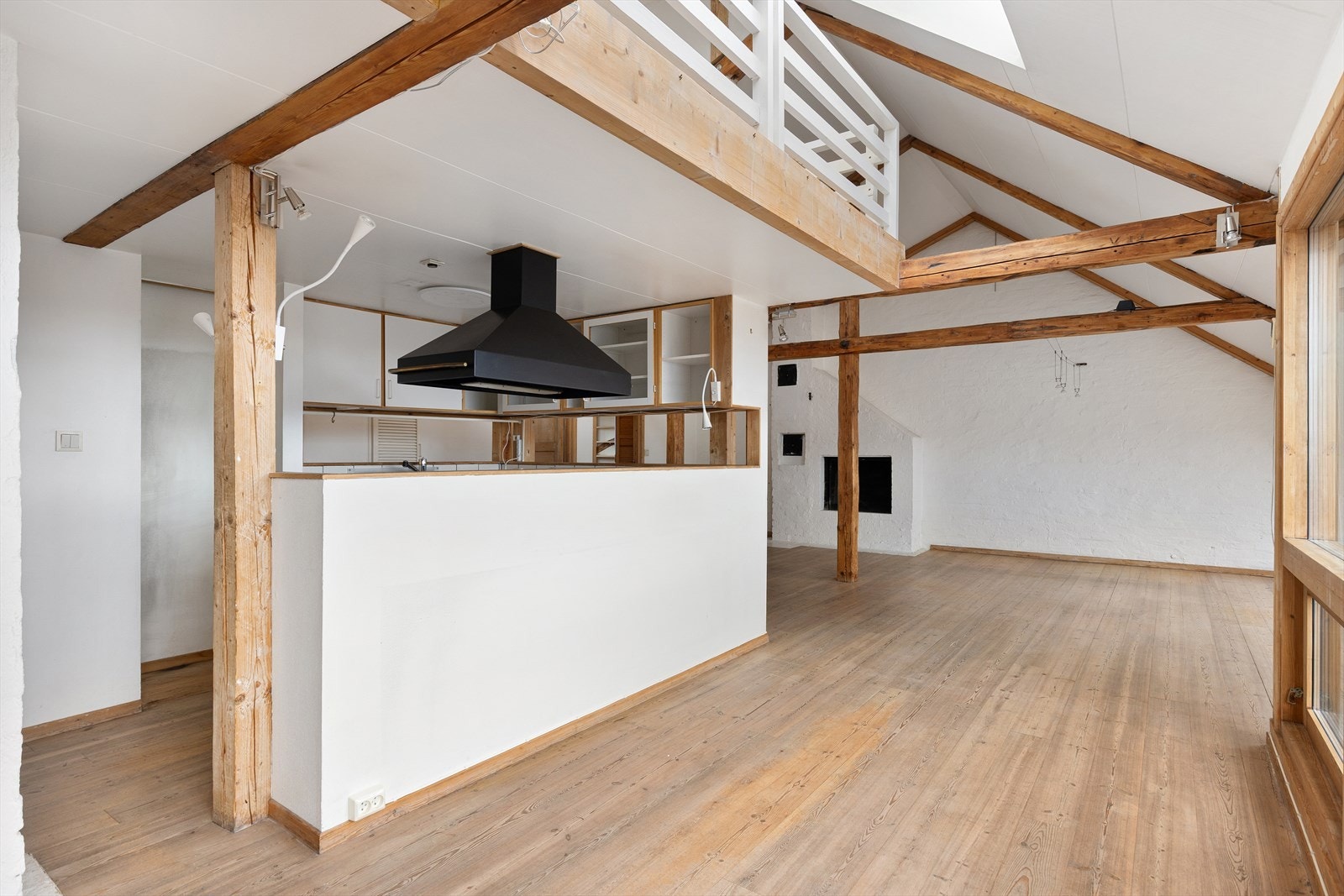 Stor stue med klassiske søyler og bjelker. Kjøkkenet plassert under loftstuen/mezzanin Galleribilde