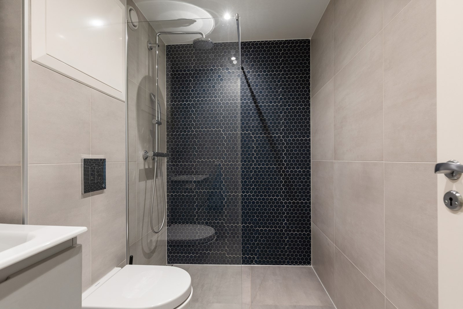 Badet byr på stilrene fliser, nedfelt servant, vegghengt toalett og romslig dusjhjørne. Galleribilde