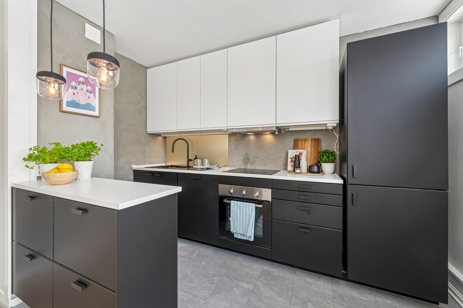 Pen kjøkkeninnredning med slette fabrikklakkerte fronter og integrerte hvitevarer; integrert stekeovn, koketopp, oppvaskmaskin og kjøl-/fryseskap. Galleribilde