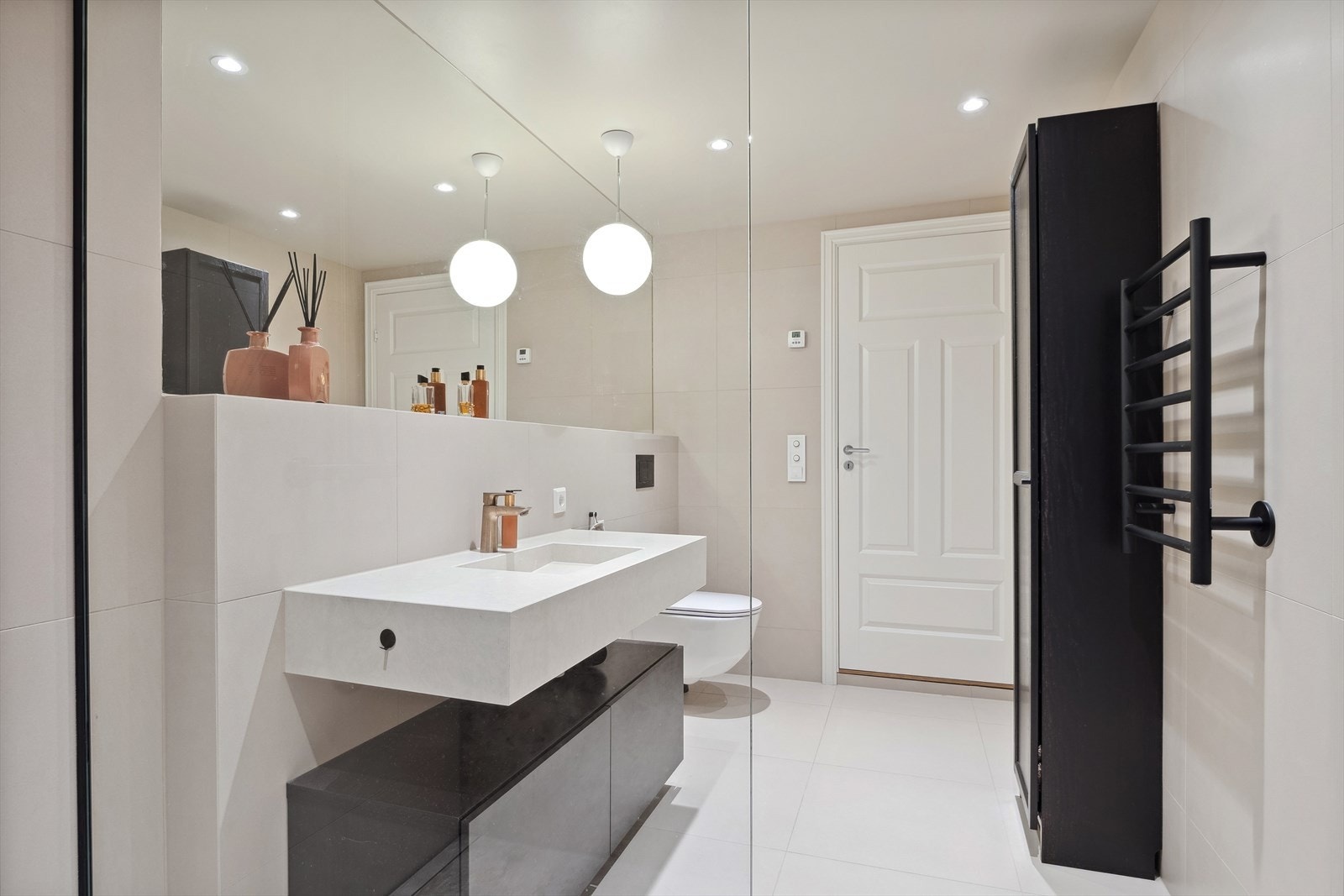 Badet har en stilig moderne servant og benk og et stort fint speil på veggen Galleribilde