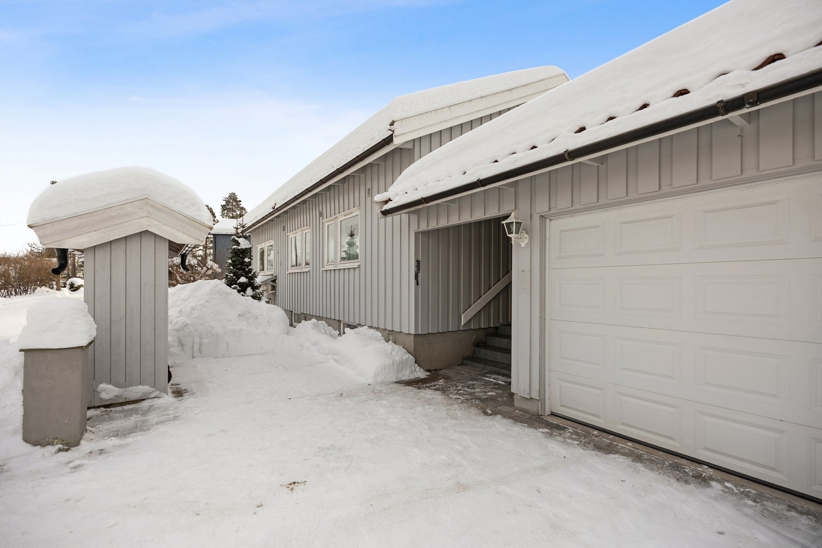 Praktisk adkomst til boligen med integrert garasje og overbygd inngangsparti. Belegningsstein i gårdsplass. Galleribilde