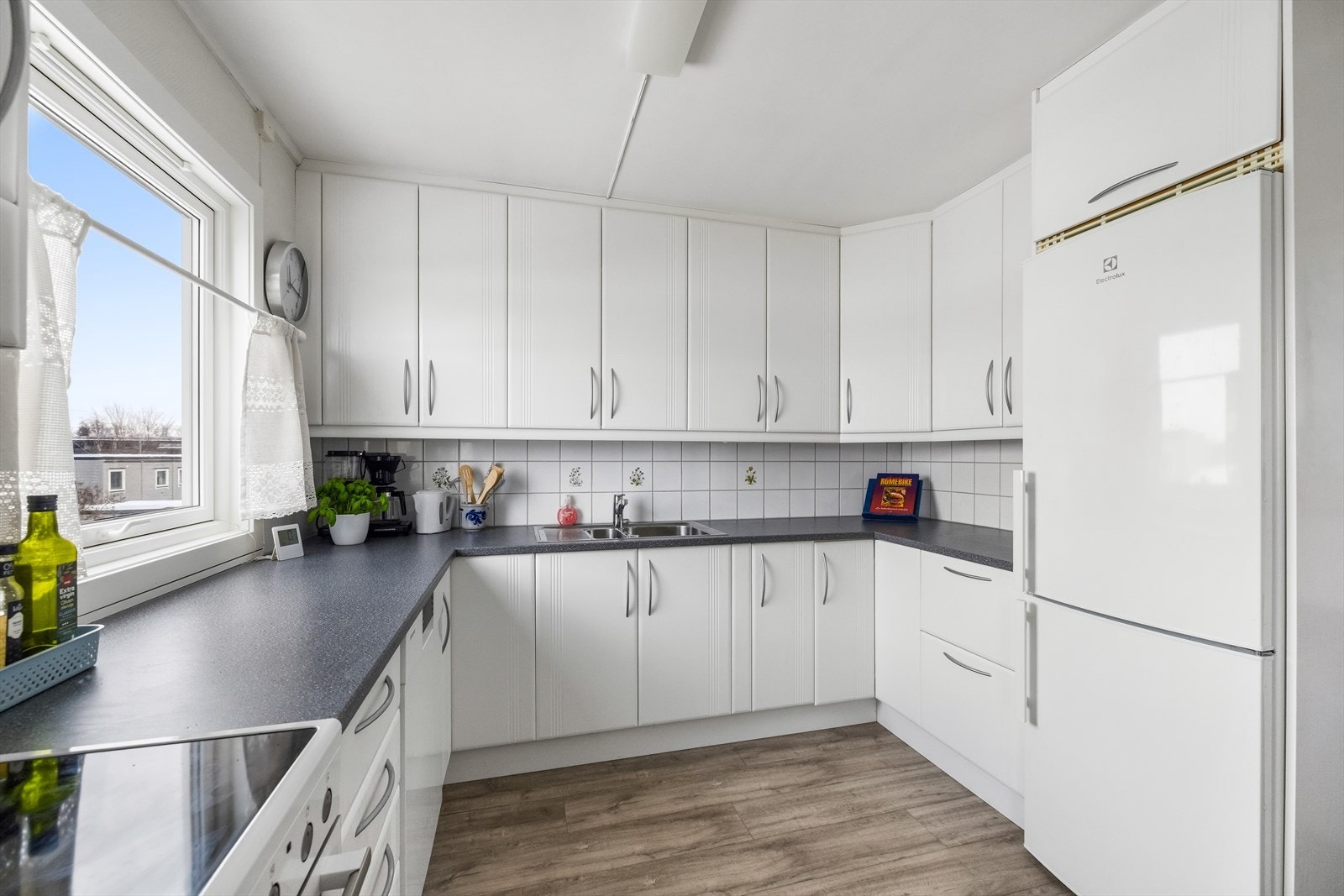 Innredningen har lyse fronter og laminat benkeplate, med fliser mellom over- og underskap som gir et tidløst og lettstelt uttrykk. Galleribilde