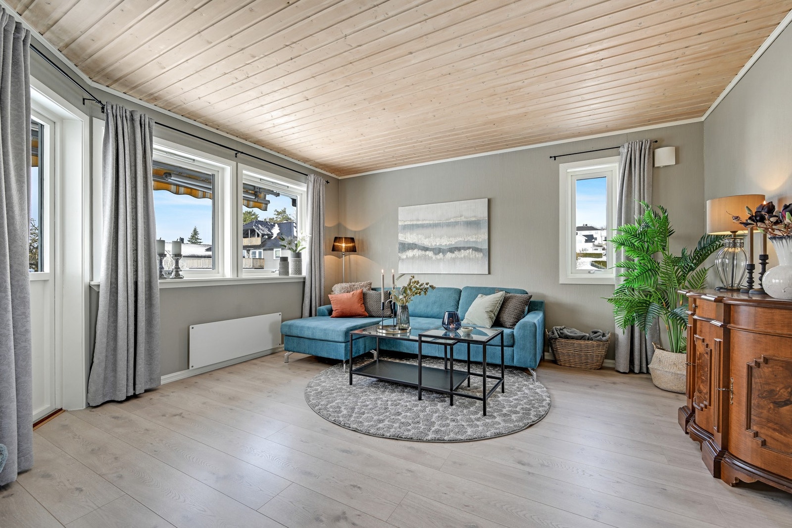 Lys og trivelig stue med pent og moderne laminatgulv, pent tapet på veggene og trepanel i himling. Galleribilde