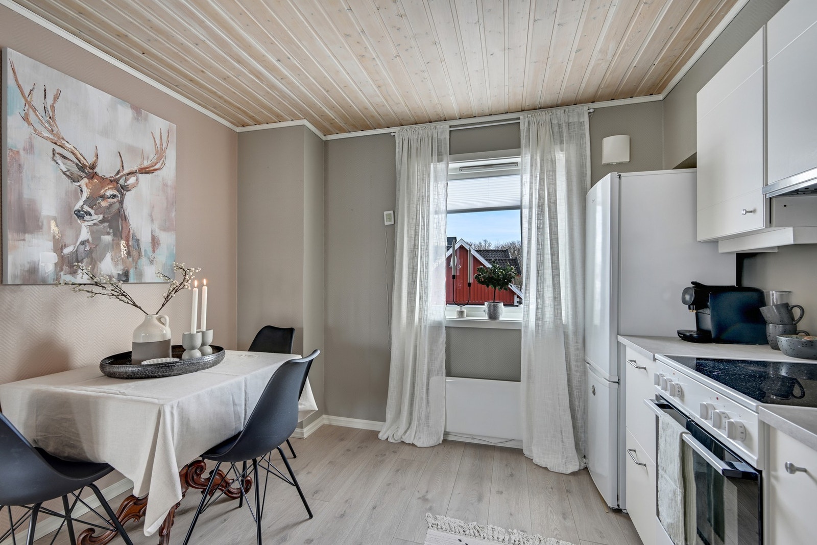 Kjøkken med pent laminatgulv, tapet på veggen malt i en delikat farge og panel i himling Galleribilde