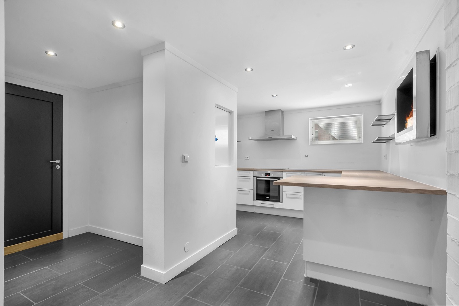 Kjøkkenet er lyst og har mye benkeplass. Dør til venstre er inngang fra garasjen. Galleribilde