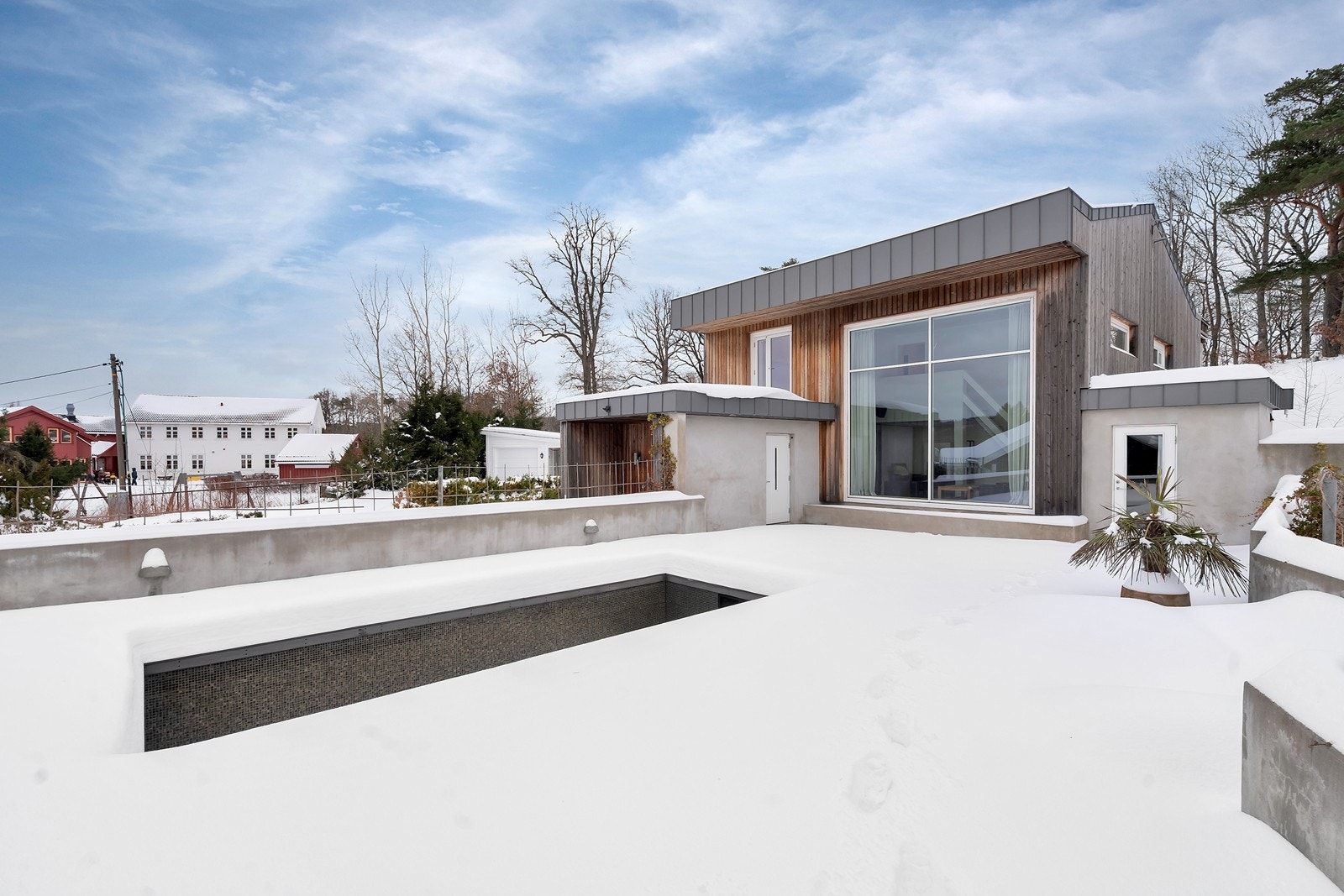 Uteområdet er av betong rundt bassenget. Døren til høyre er eget bodrom for lagring. Galleribilde