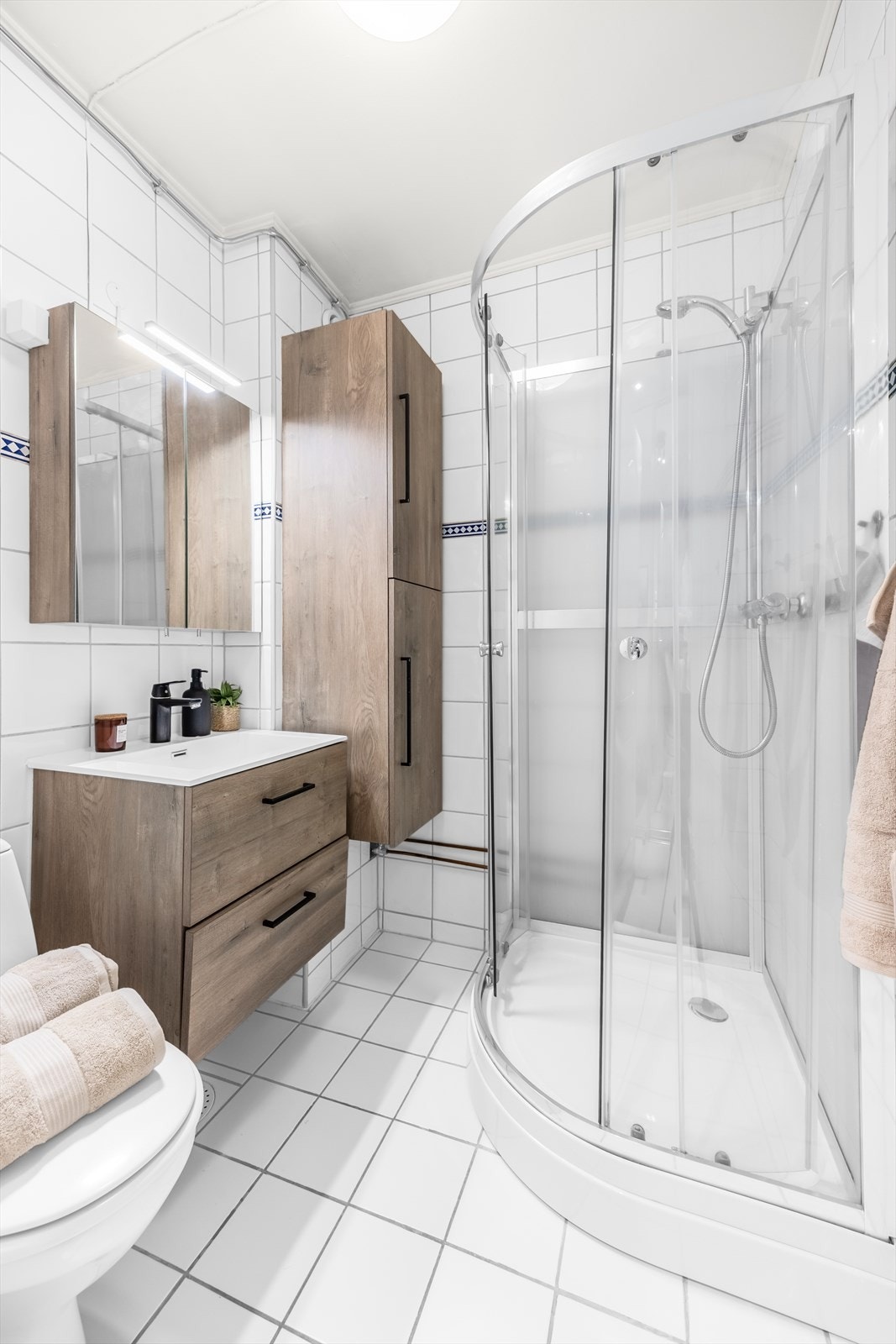 Leiligheten har et flislagt baderom med en moderne baderomsinnredning Galleribilde