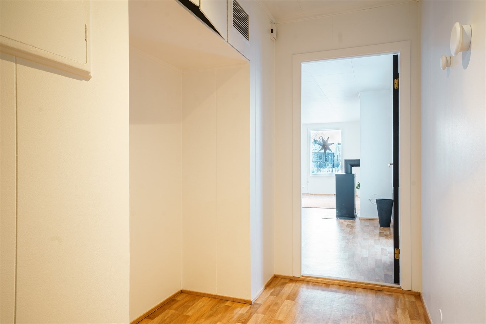 Lys og innbydende gang som leder inn til en romslig stue med store vinduer. Galleribilde