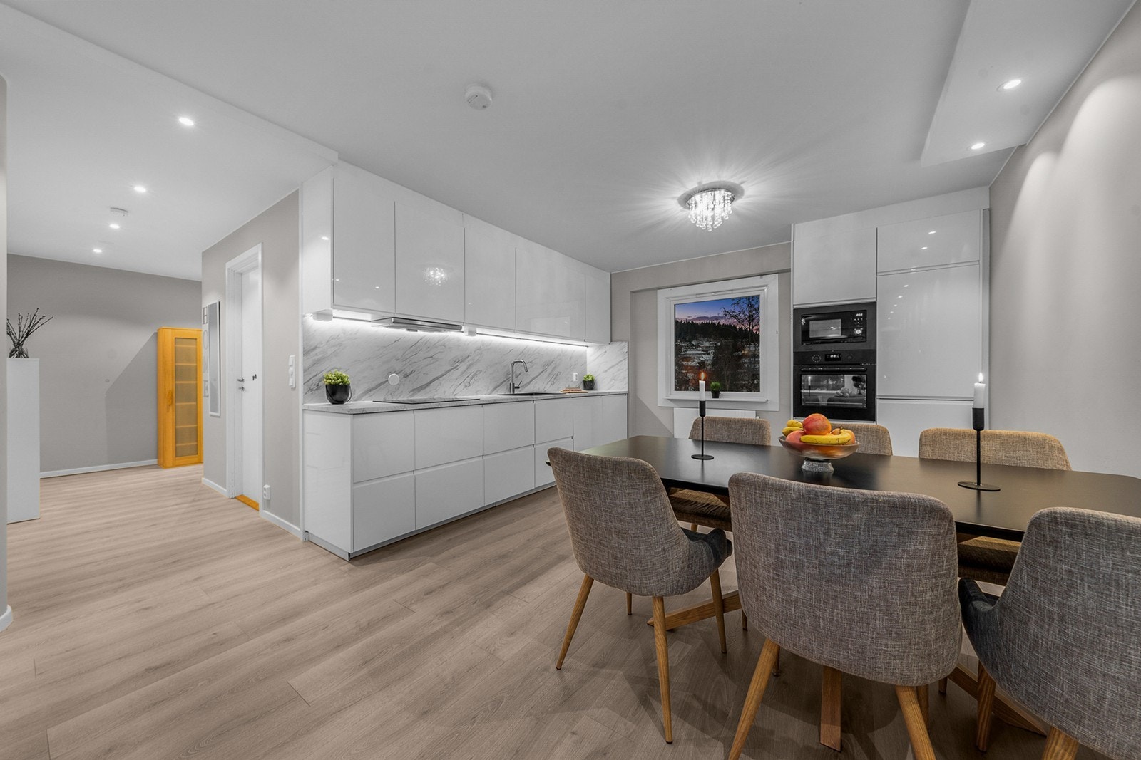 Kjøkkenet ligger i en åpen og sosial løsning mot stuen, og har glatte, hvite fronter kombinert med laminat benkeplate og nedfelt vaskekum Galleribilde