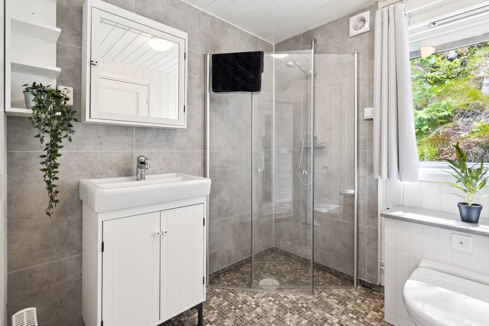 Pent bad med belegg på gulv og baderomsplater på vegg. Innredet med baderomsinnredning, toalett (Jets-vakum) og dusjløsning. Galleribilde