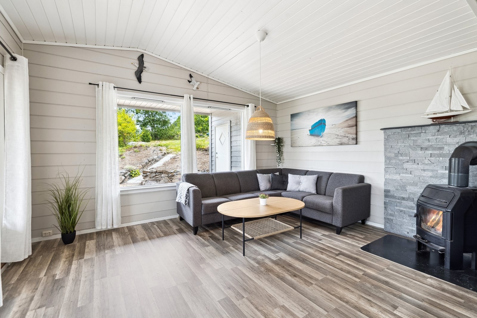 Stuens utforming gir muligheter for innredning i ulike soner og på kalde dager er det godt med varme fra vedovnen i hjørnet. Galleribilde