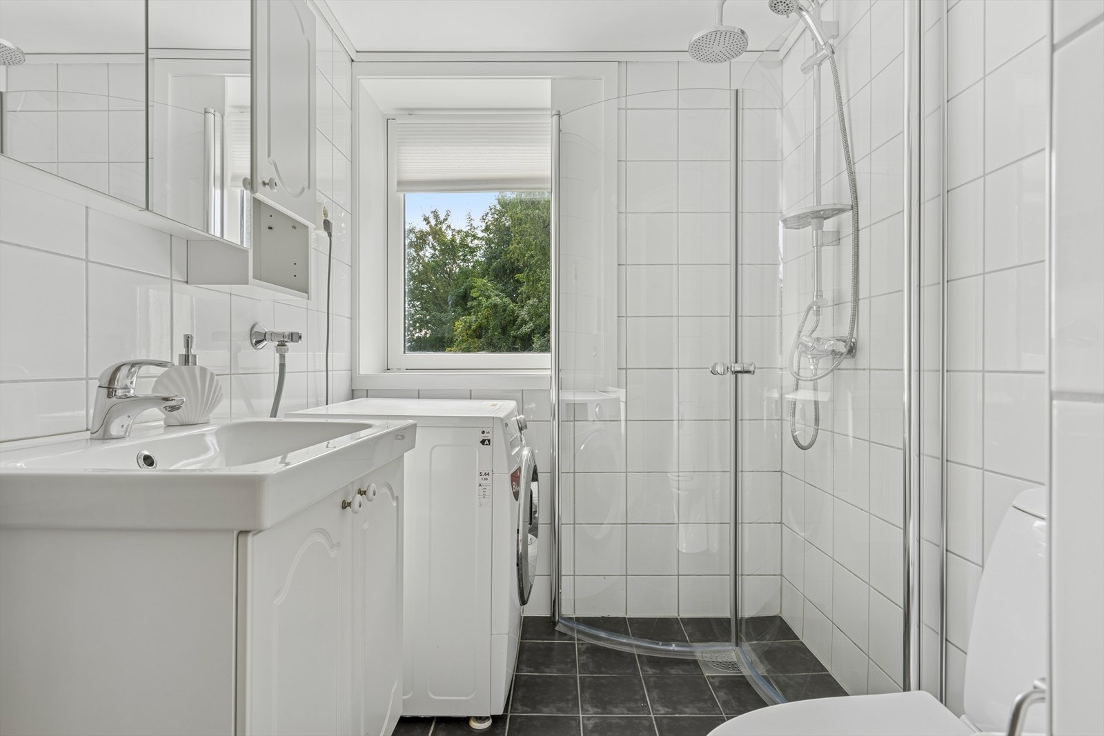 Arealeffektivt og tidløst baderom som måler 3,4 kvm. Flis på gulv og vegg, malt slett himling. Galleribilde