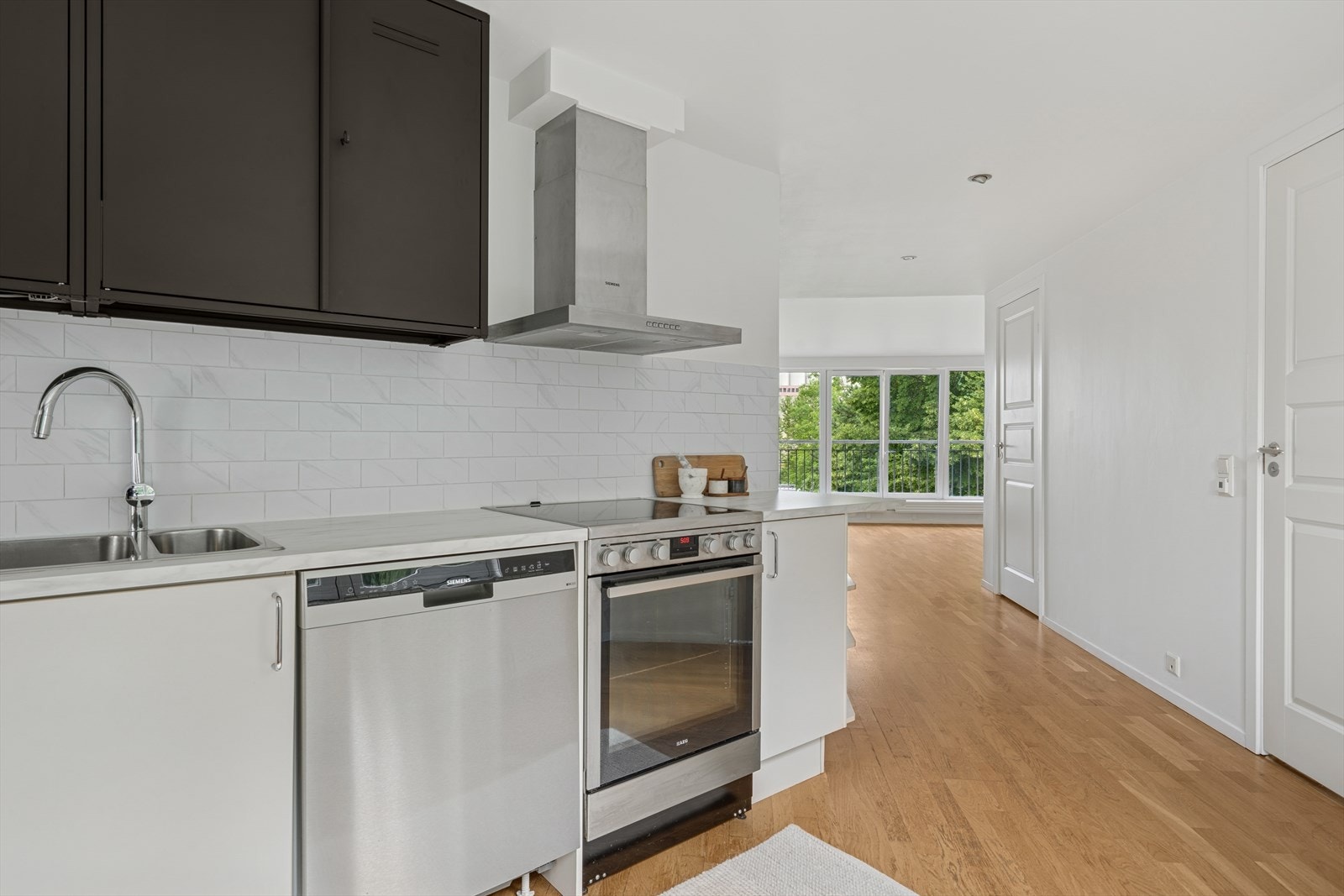 Kjøkkenet er innredet med folierte skrog og av metall med slette fronter og laminert benkeplate. Laminatfliser på vegg over benkeplate. Galleribilde