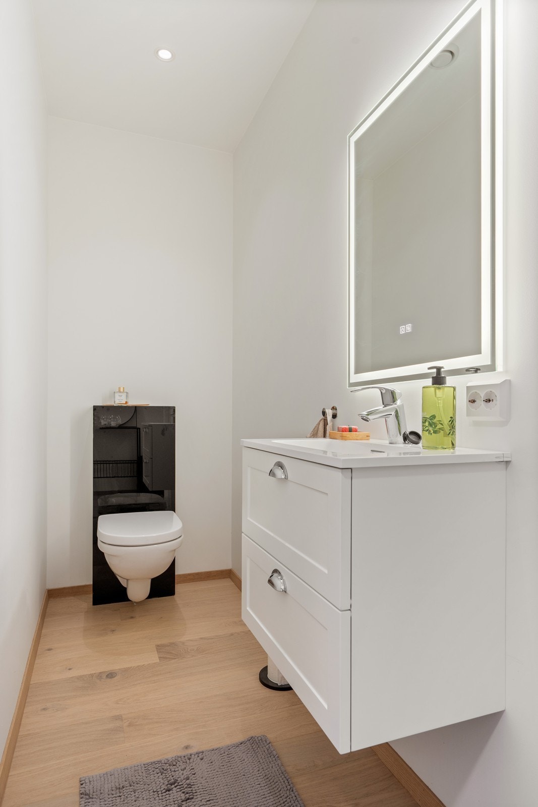 Vegg i vegg med badet ligger et toalettrom som inneholder servant i møblement, speil m/belysning og vegghengt toalett. Galleribilde