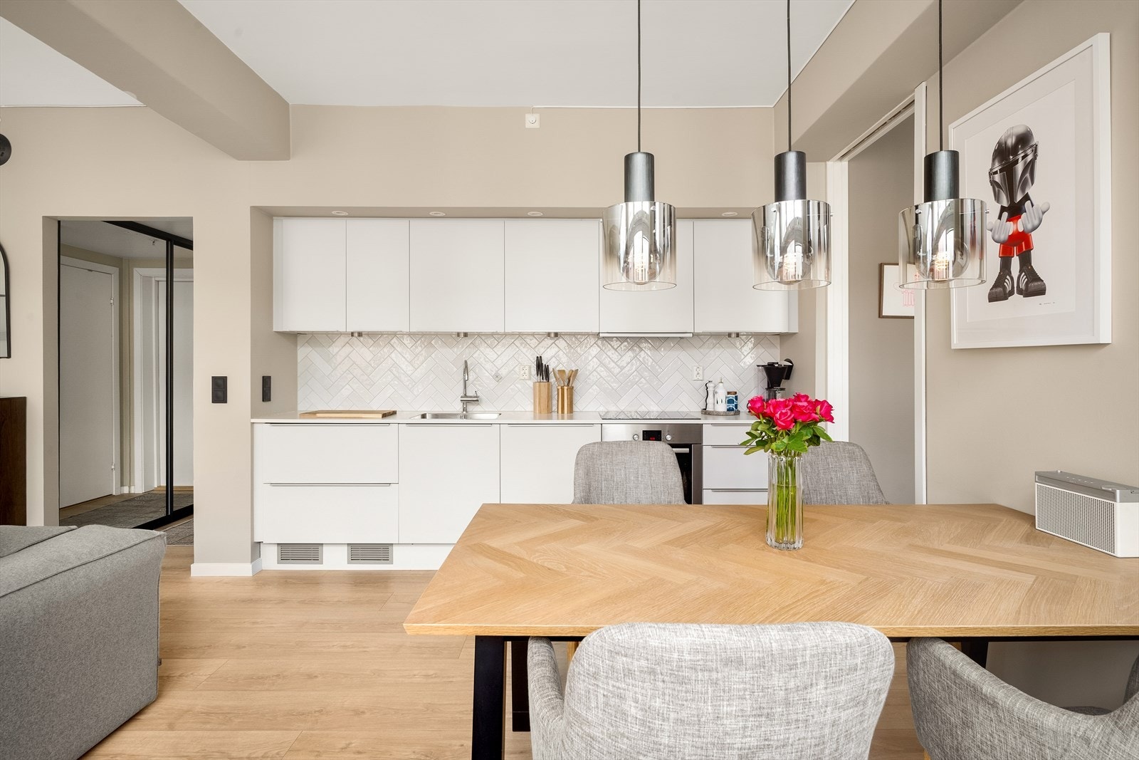 Lys innredning med glatte fronter, fliser på vegg over kjøkkenbenk og benkeplate i laminat. Flisene ble lagt i 2021. Galleribilde