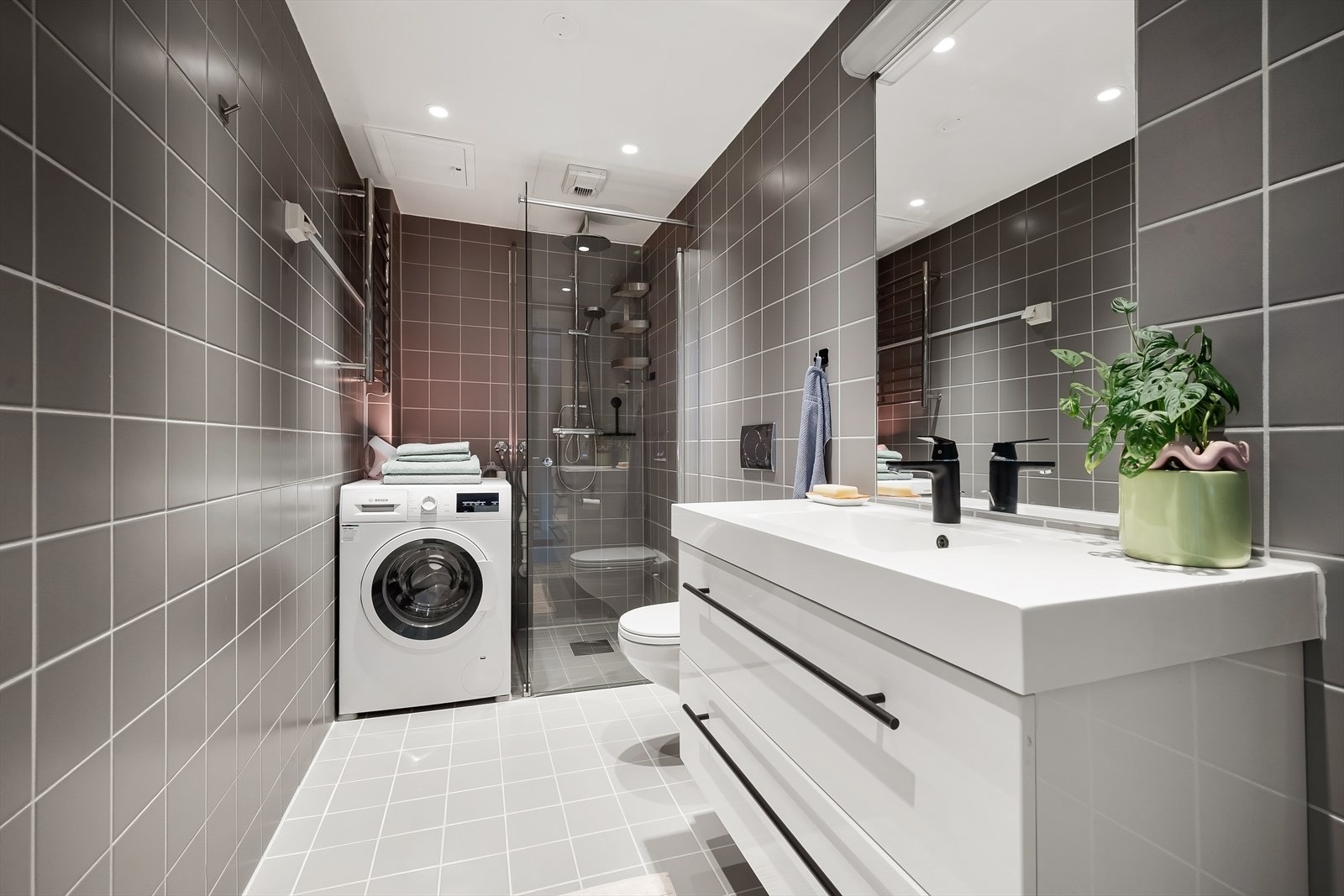 Romslig og funksjonelt bad med flislagte overflater, innfelte downlights og elektrisk gulvvarme. Galleribilde