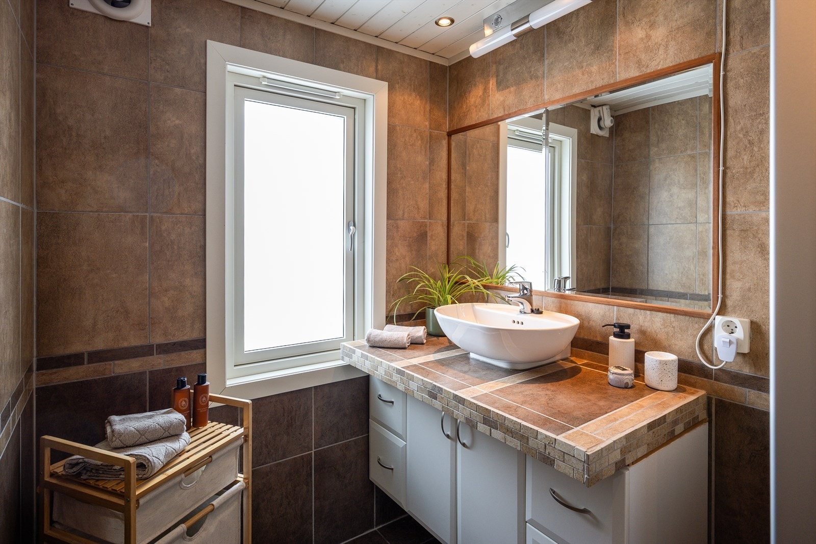 Badet er utstyrt med dusjkabinett, vegghengt toalett, innredning med servant og varmekabler i gulv. Galleribilde