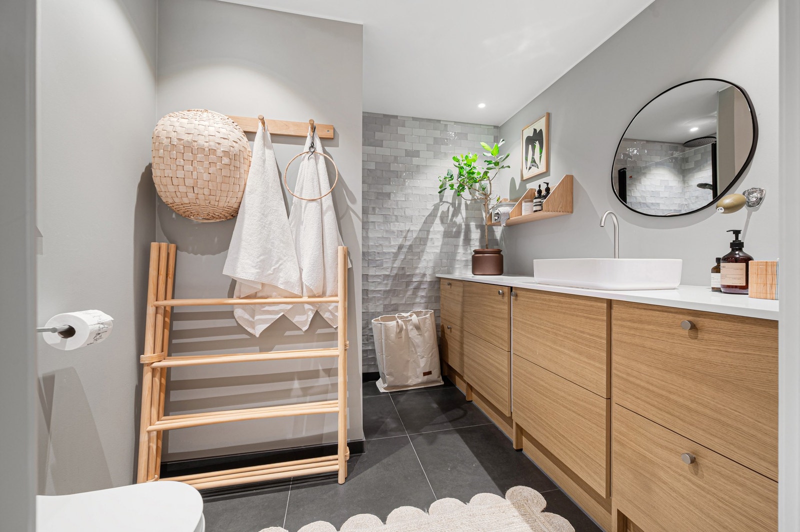 Lyst og innbydende baderom med dusj, vegghengt toalett og servant på underskap og speil. Galleribilde