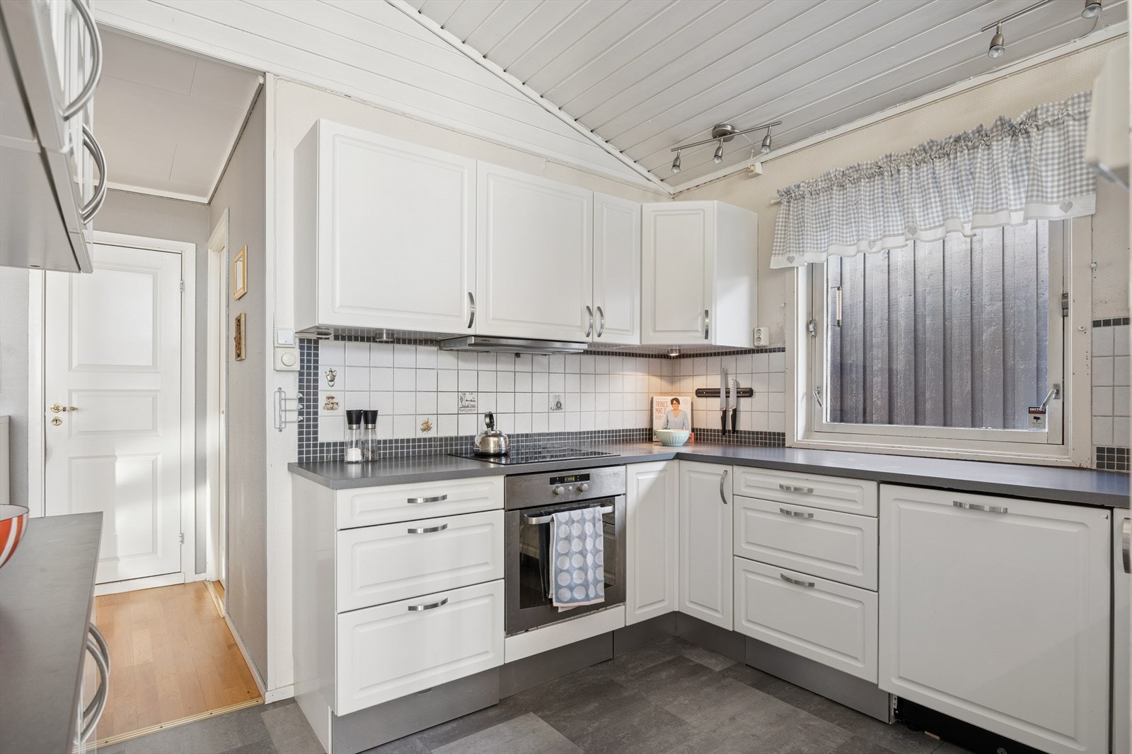 Kjøkkenet er i hvite klassiske fronter med en grå benkeplate. Galleribilde