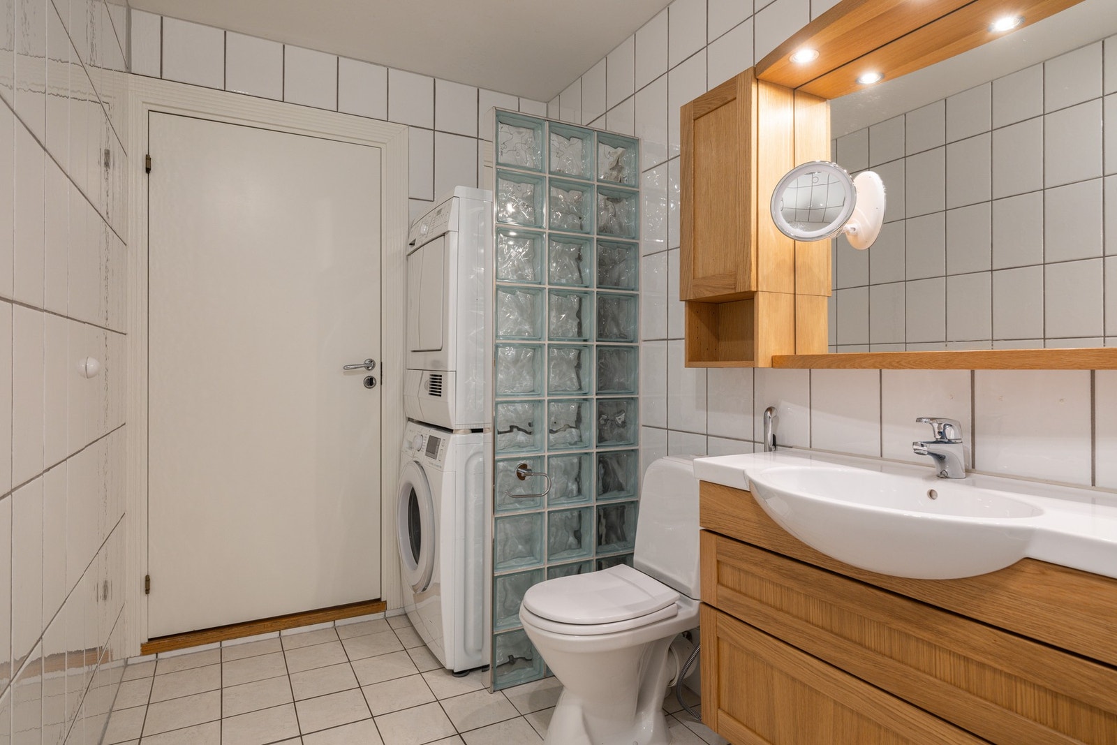 Romslig kombinert bad og vaskerom med fliser på gulv og vegger samt varmekabler i gulv. Galleribilde